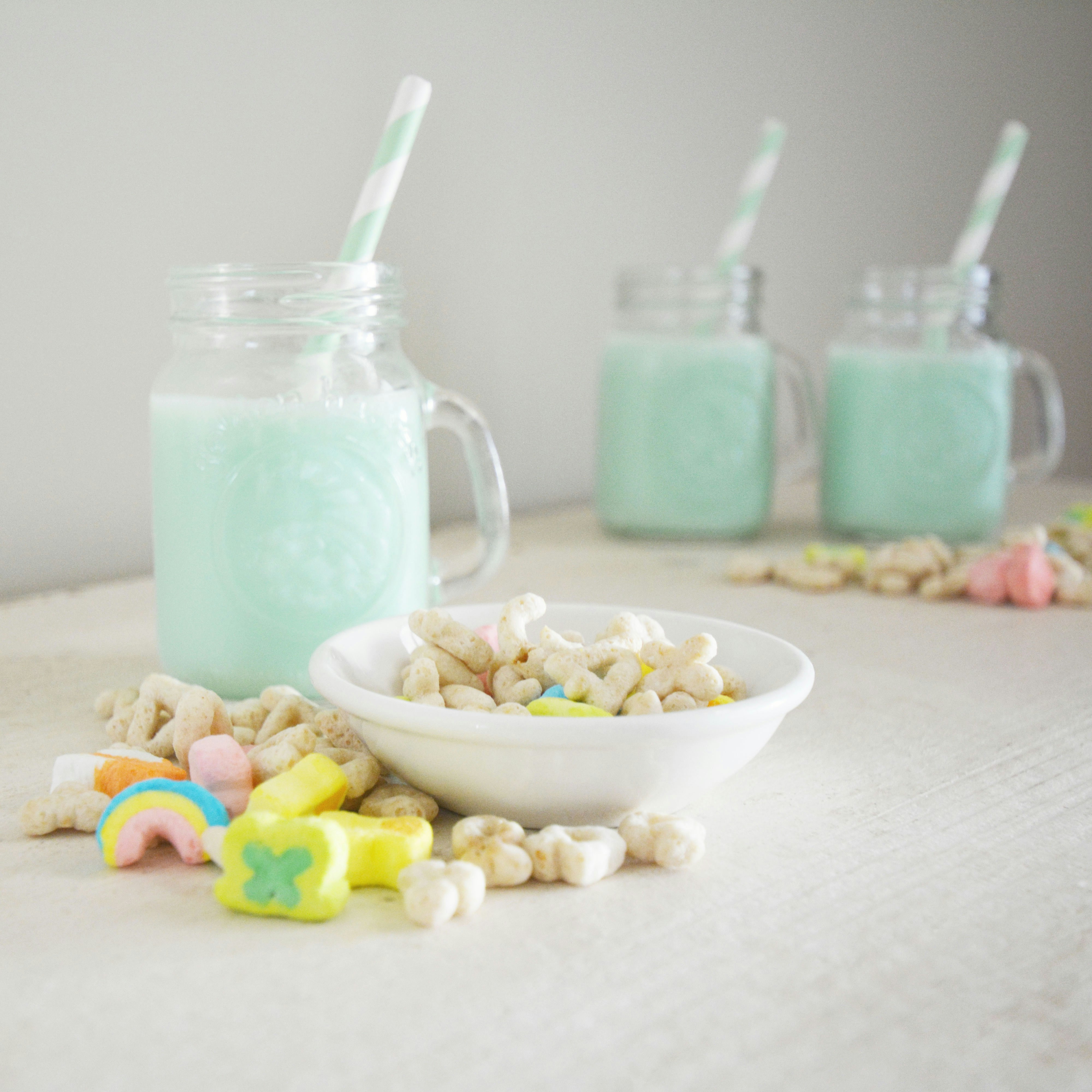 Tres vasos de leche azul con cereales y malvaviscos