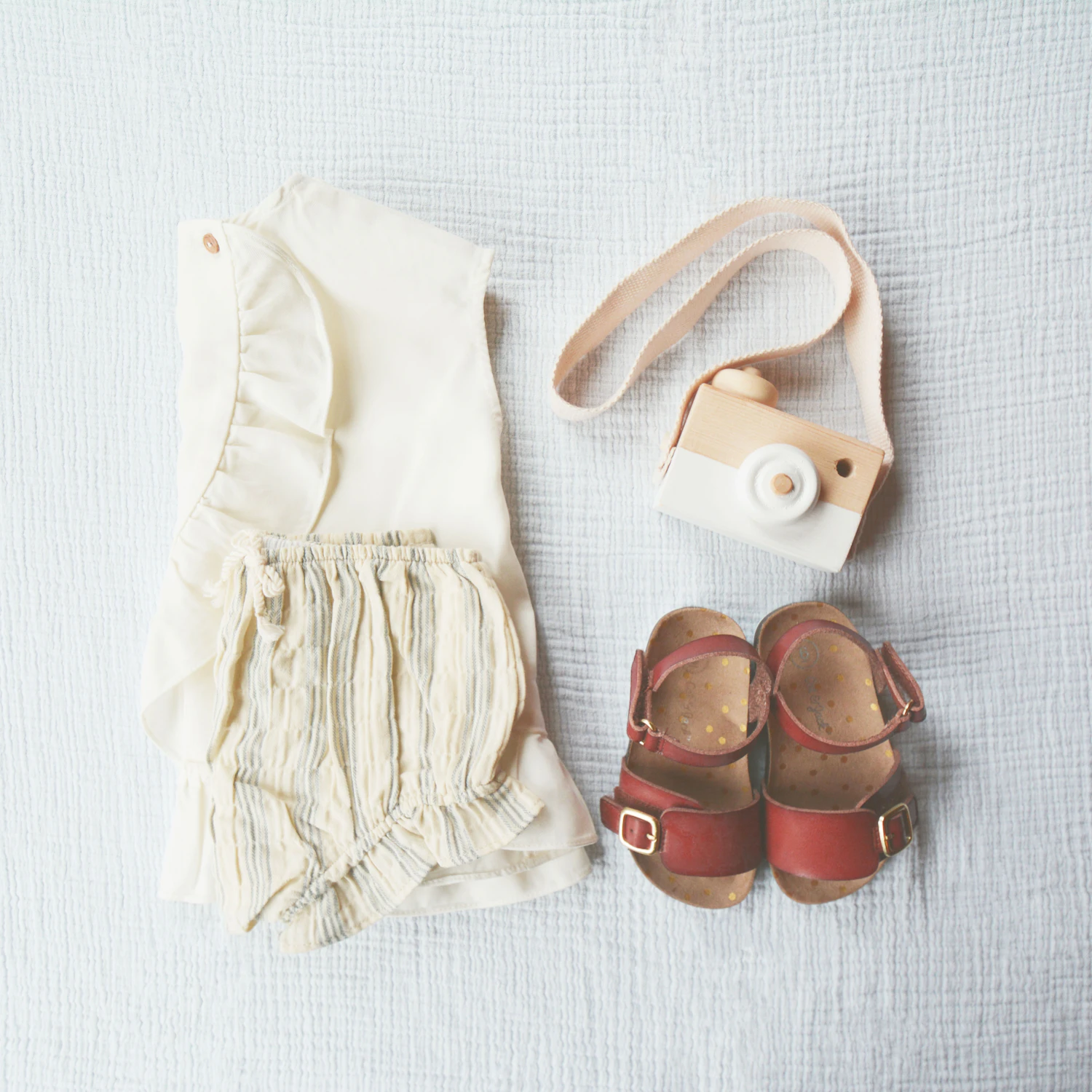 The Marsk everyday set laid out beside a pair of sandals and a toy camera