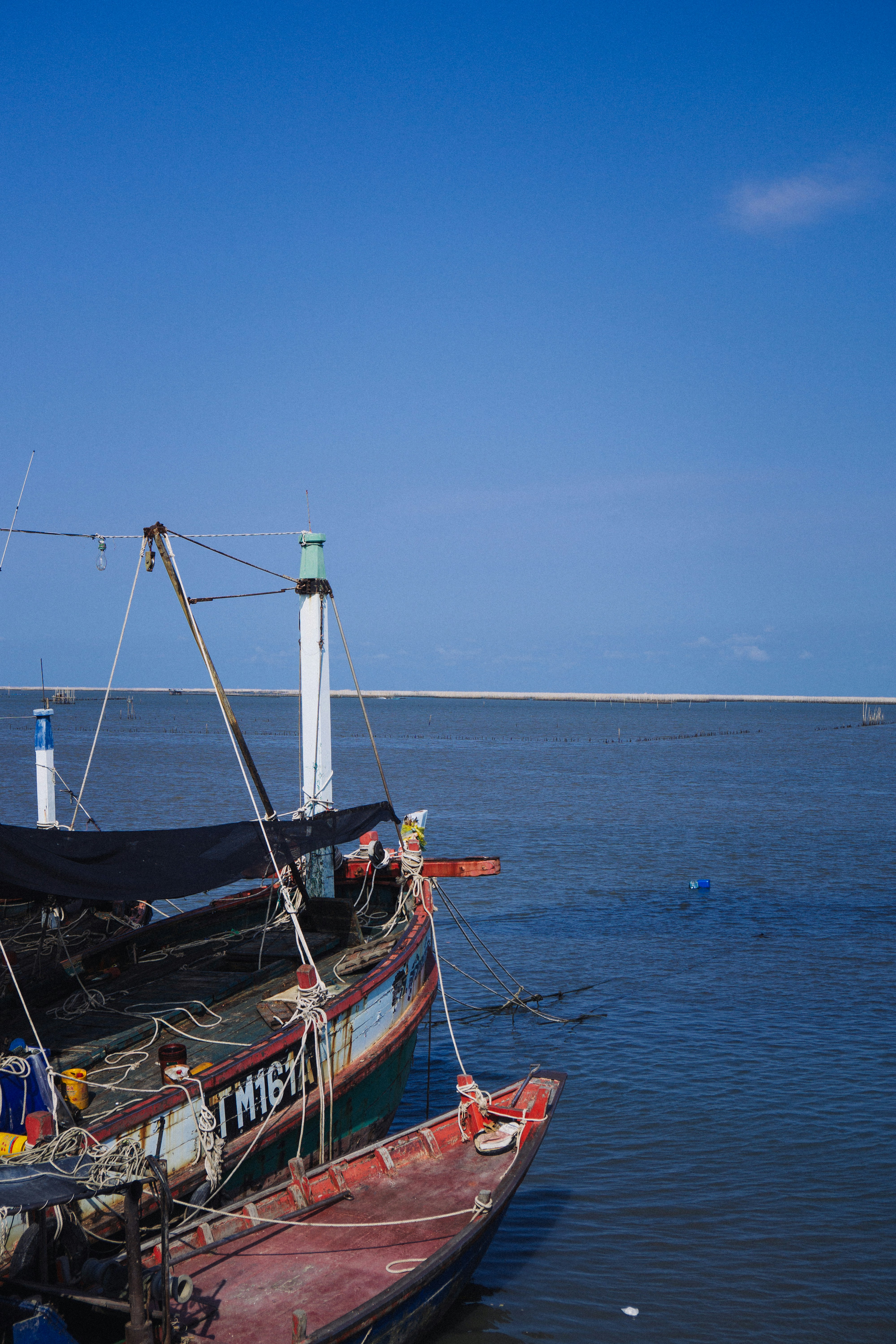 Dua perahu berlabuh di laut biru yang tenang.