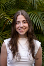 Young woman smiling in front of green foliage