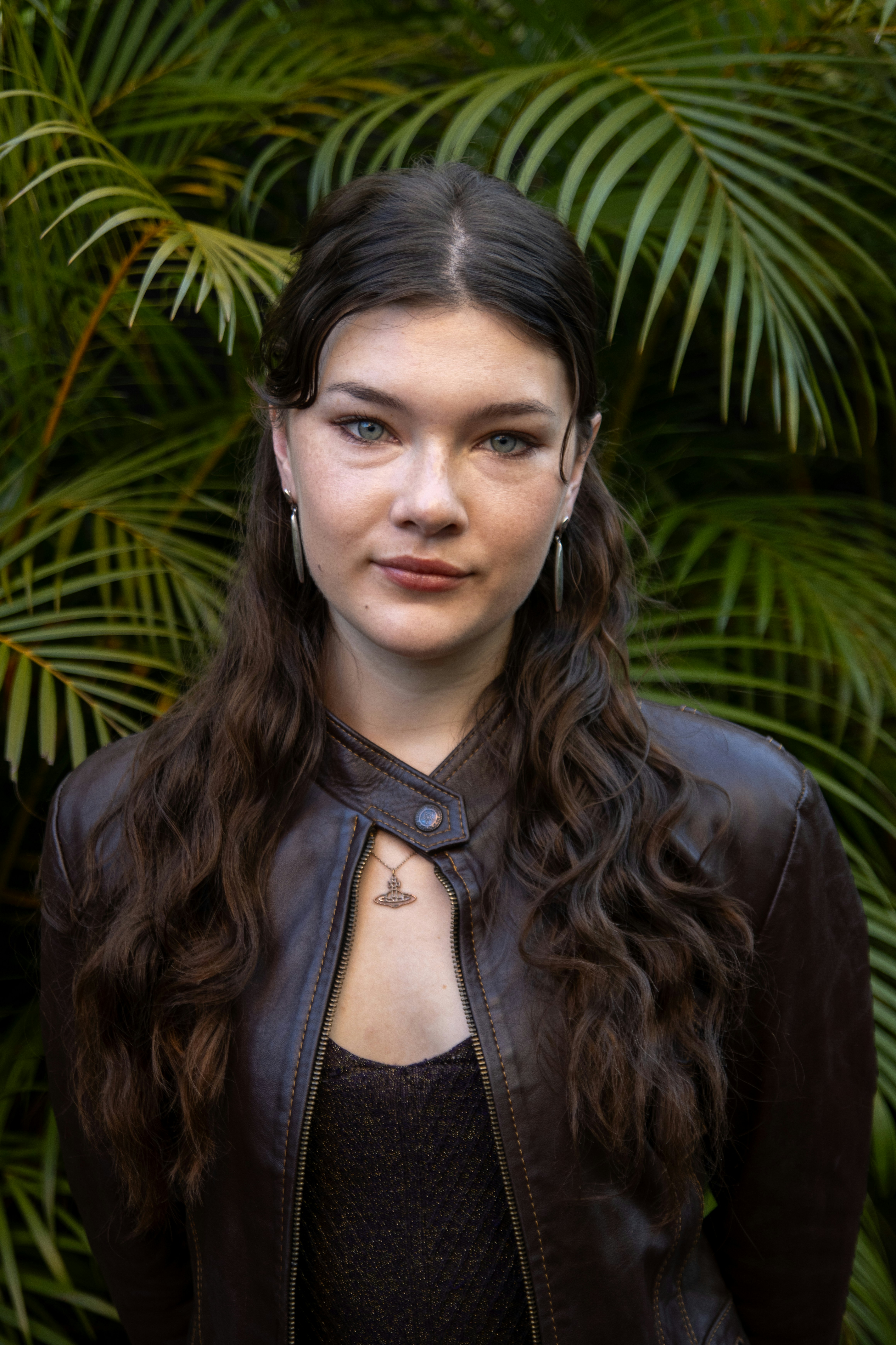 Young woman with dark wavy hair and leather jacket.