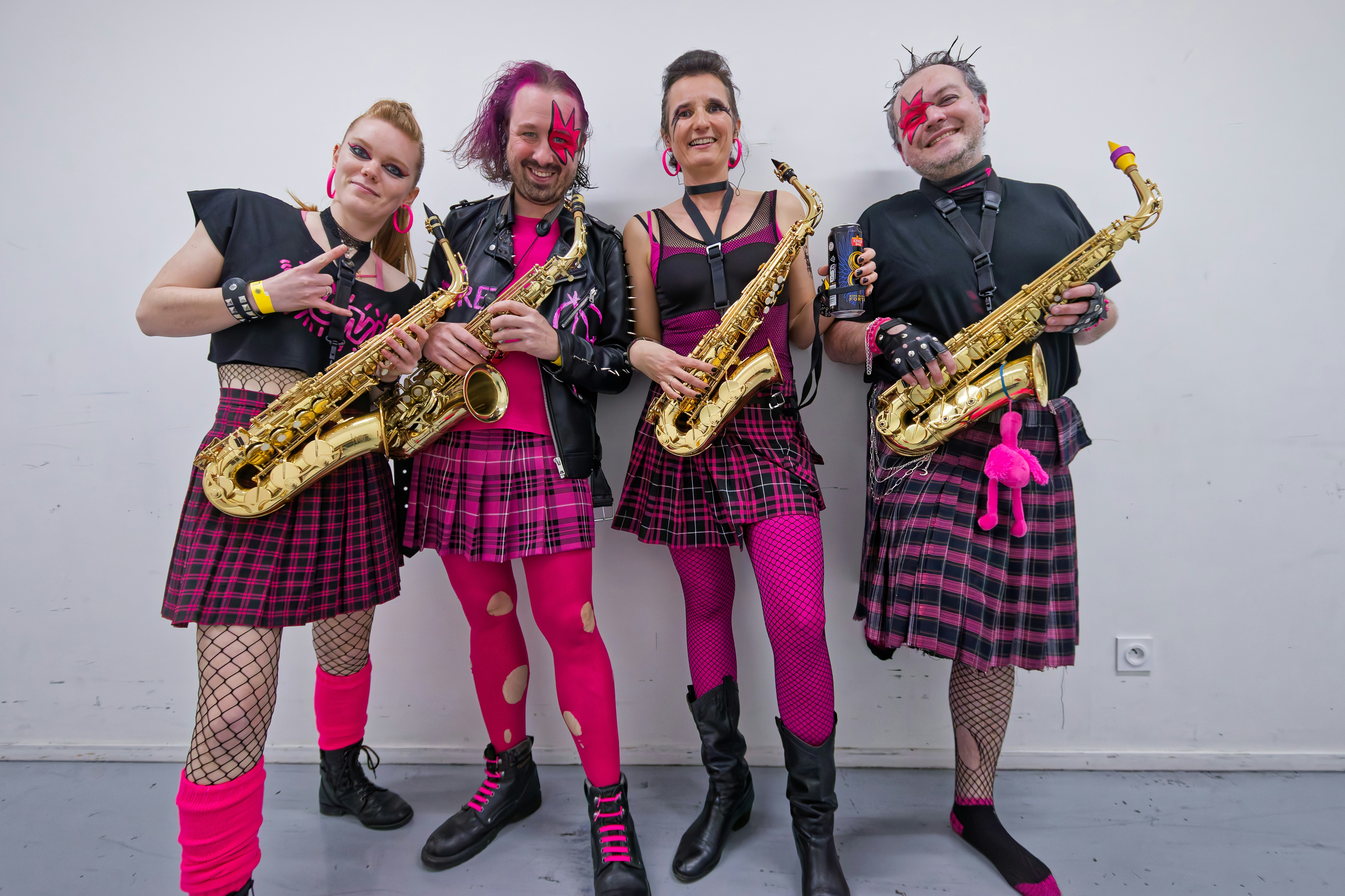 Four musicians in punk attire holding saxophones