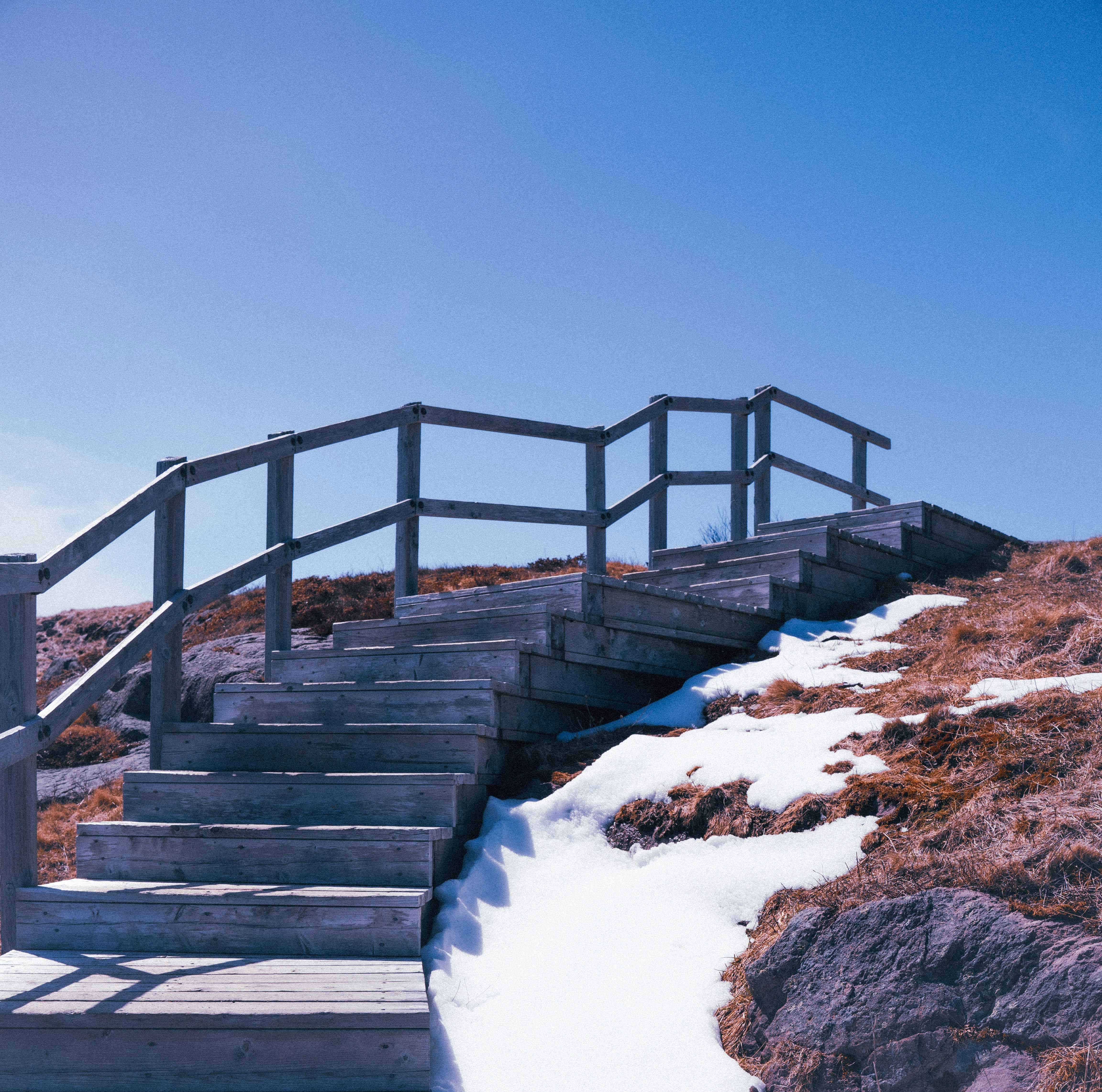 Escaleras de madera suben una colina nevada bajo un cielo despejado