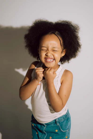 A young girl with an afro laughs heartily laughs