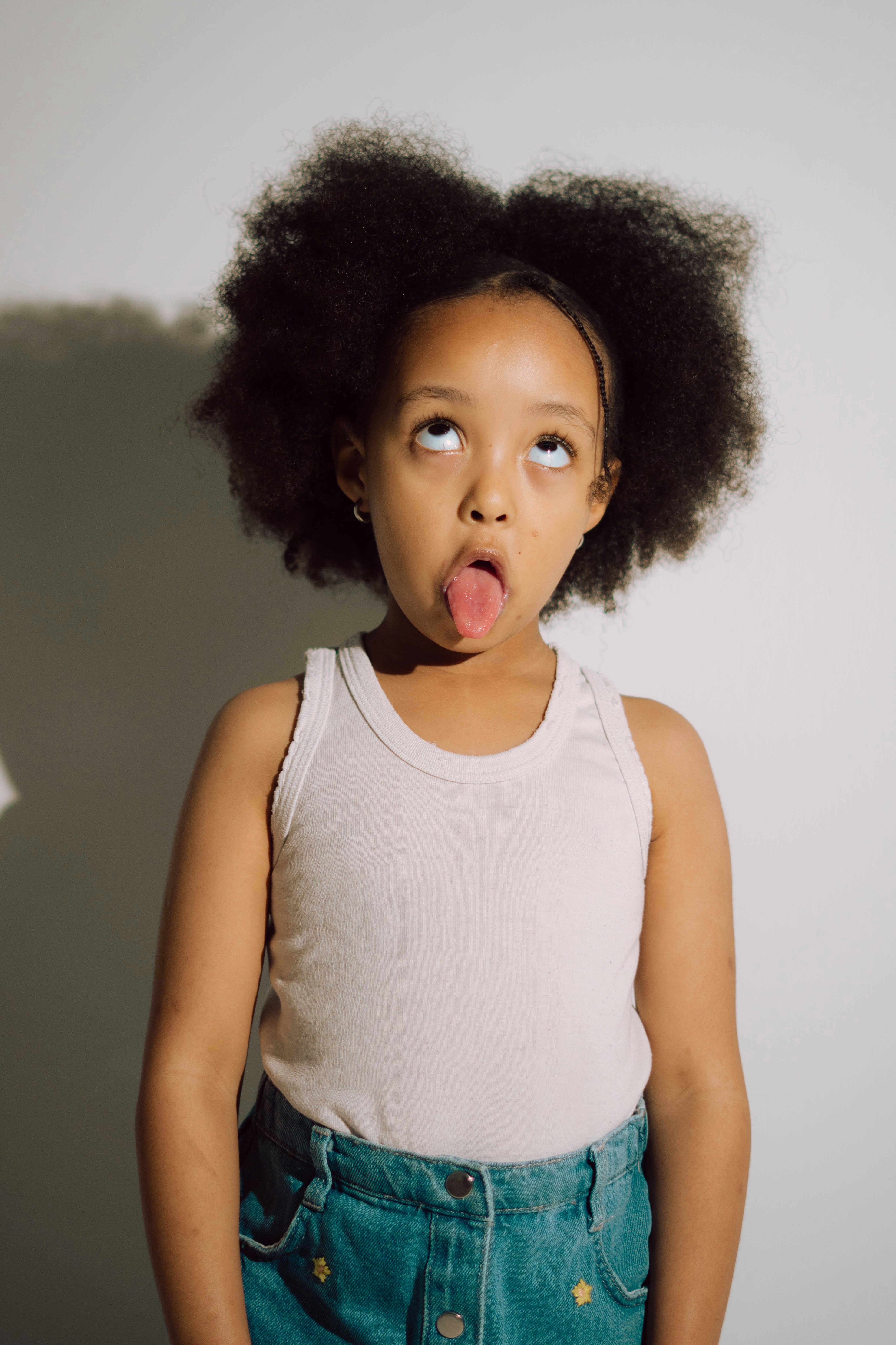 Ragazza giovane con l'afro che sporge la lingua