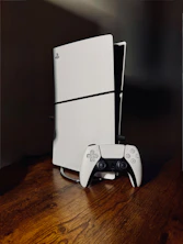 White playstation 5 console with controller on wooden table