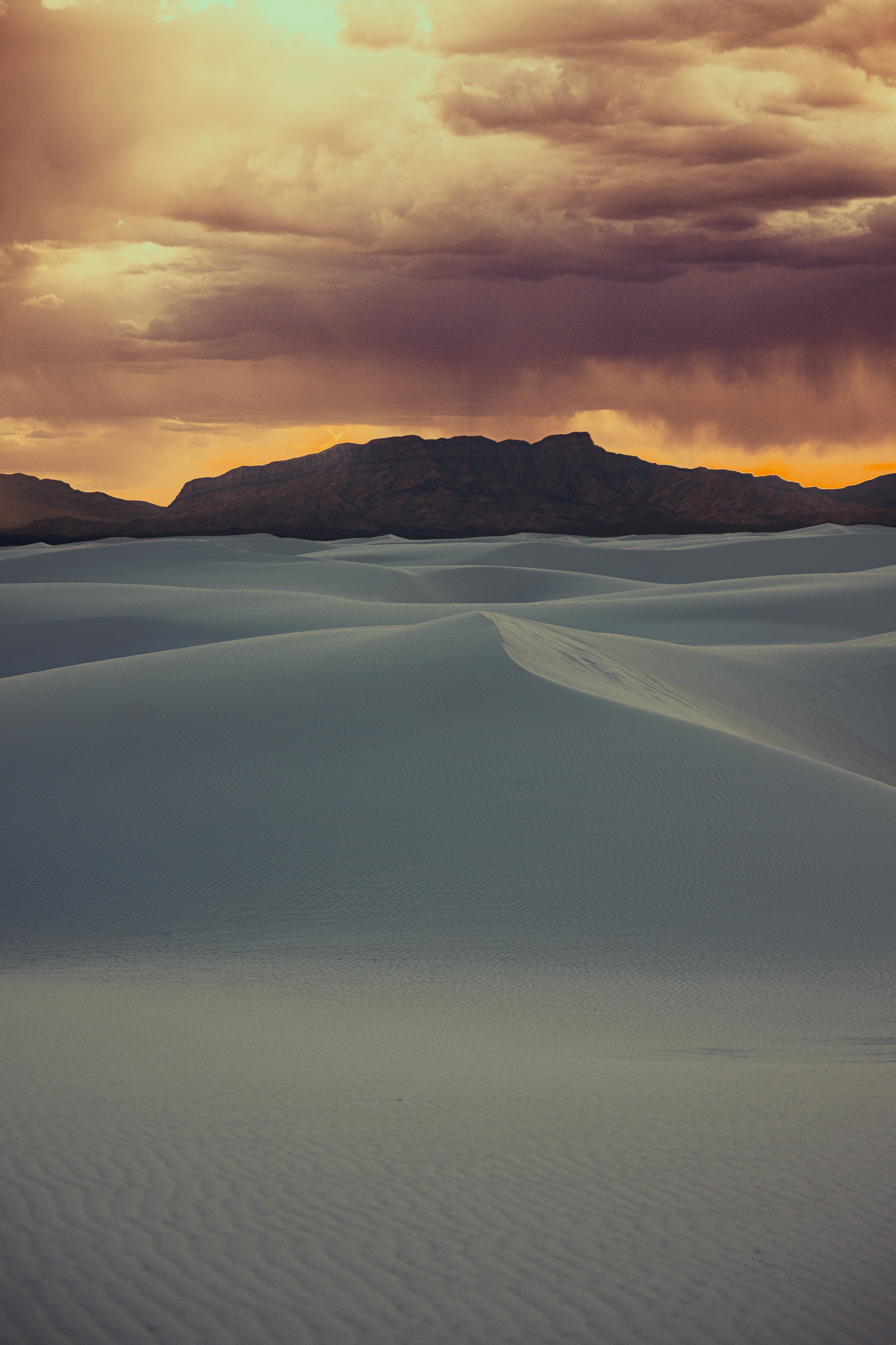 Dramatic sunset over rolling white sand dunes