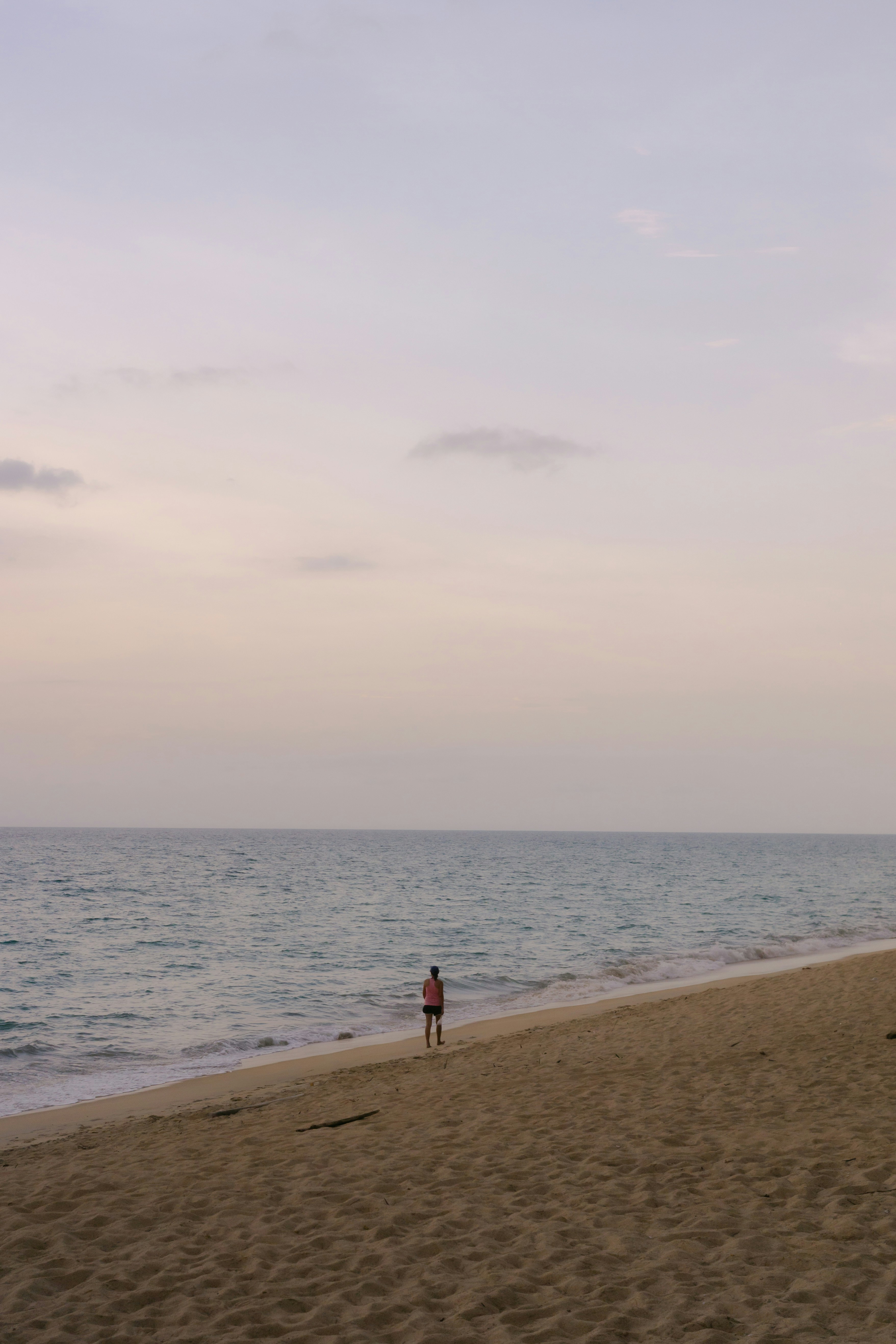 Person standing on a sandy beach by the ocean