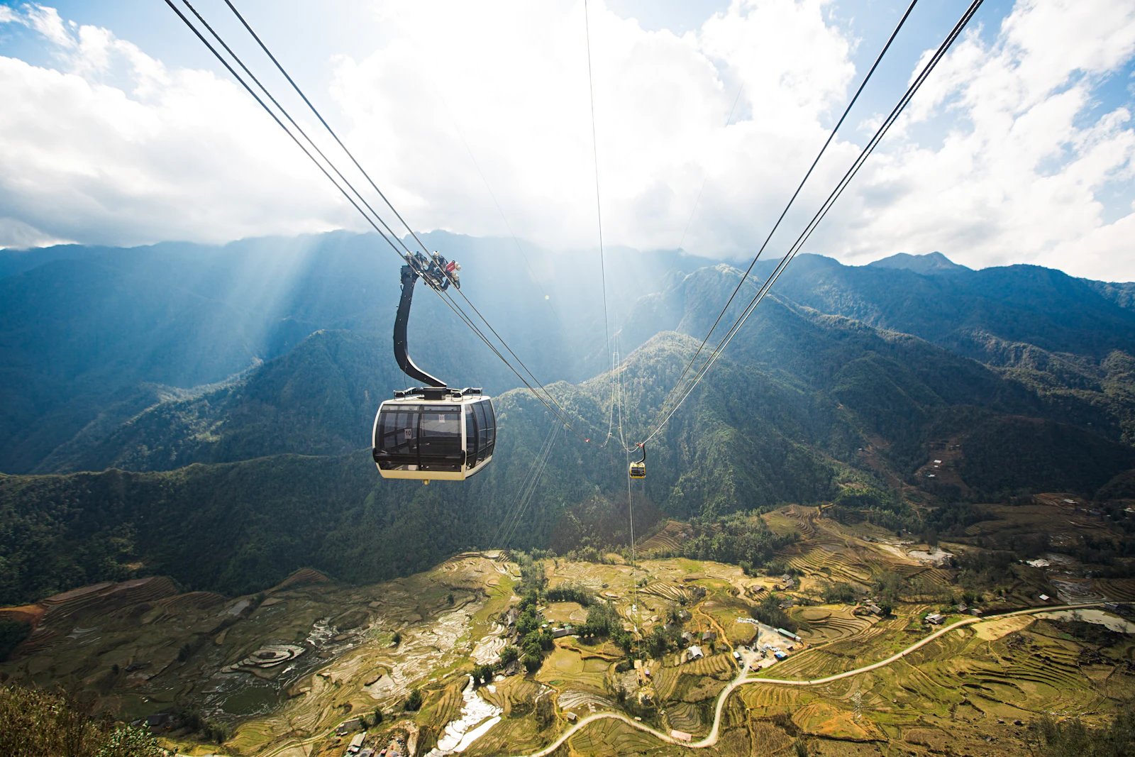 Cable car moving above green mountain landscape near Fansipan and Sapa, Vietnam