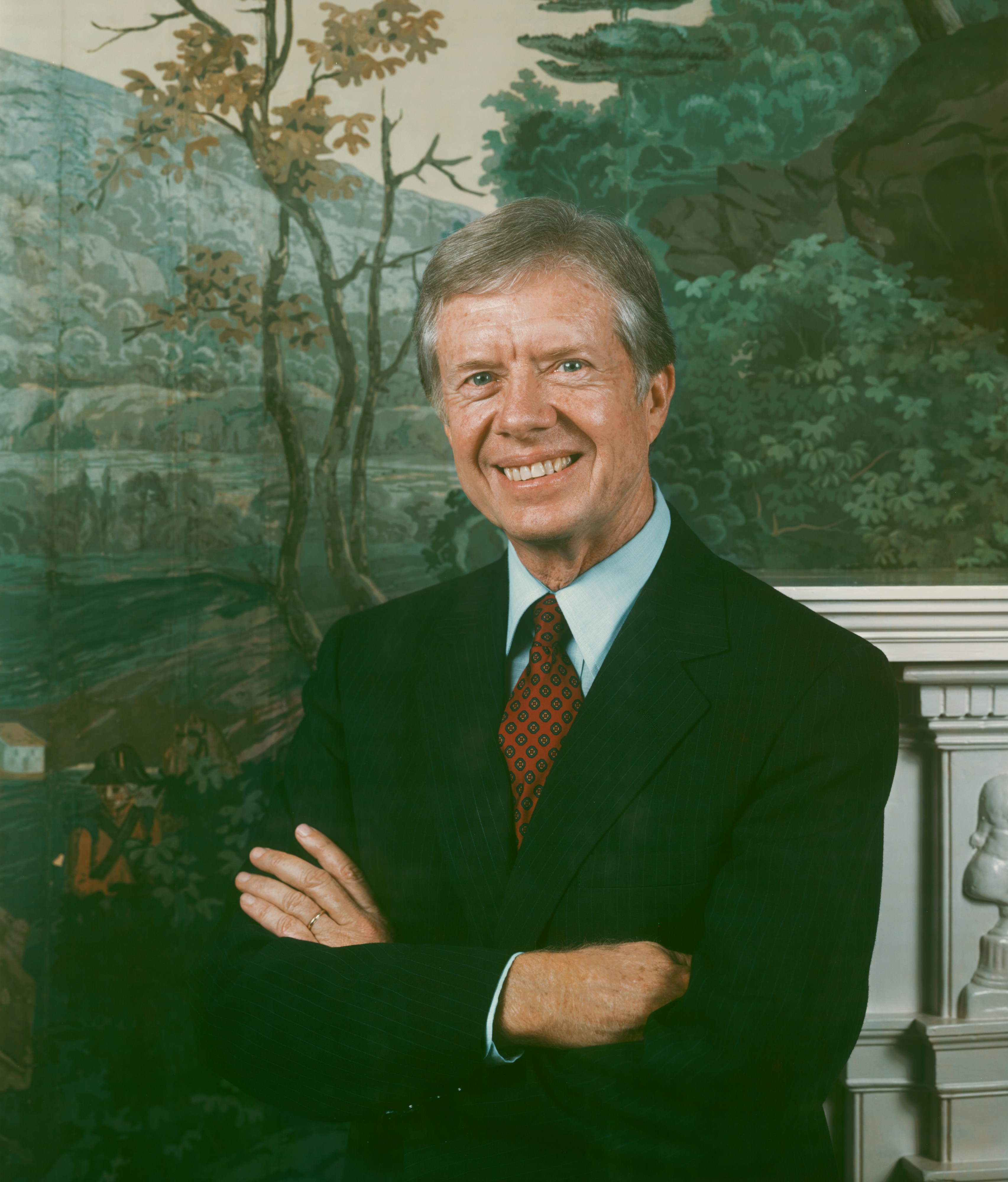 Jimmy Carter sonríe con los brazos cruzados con un traje.