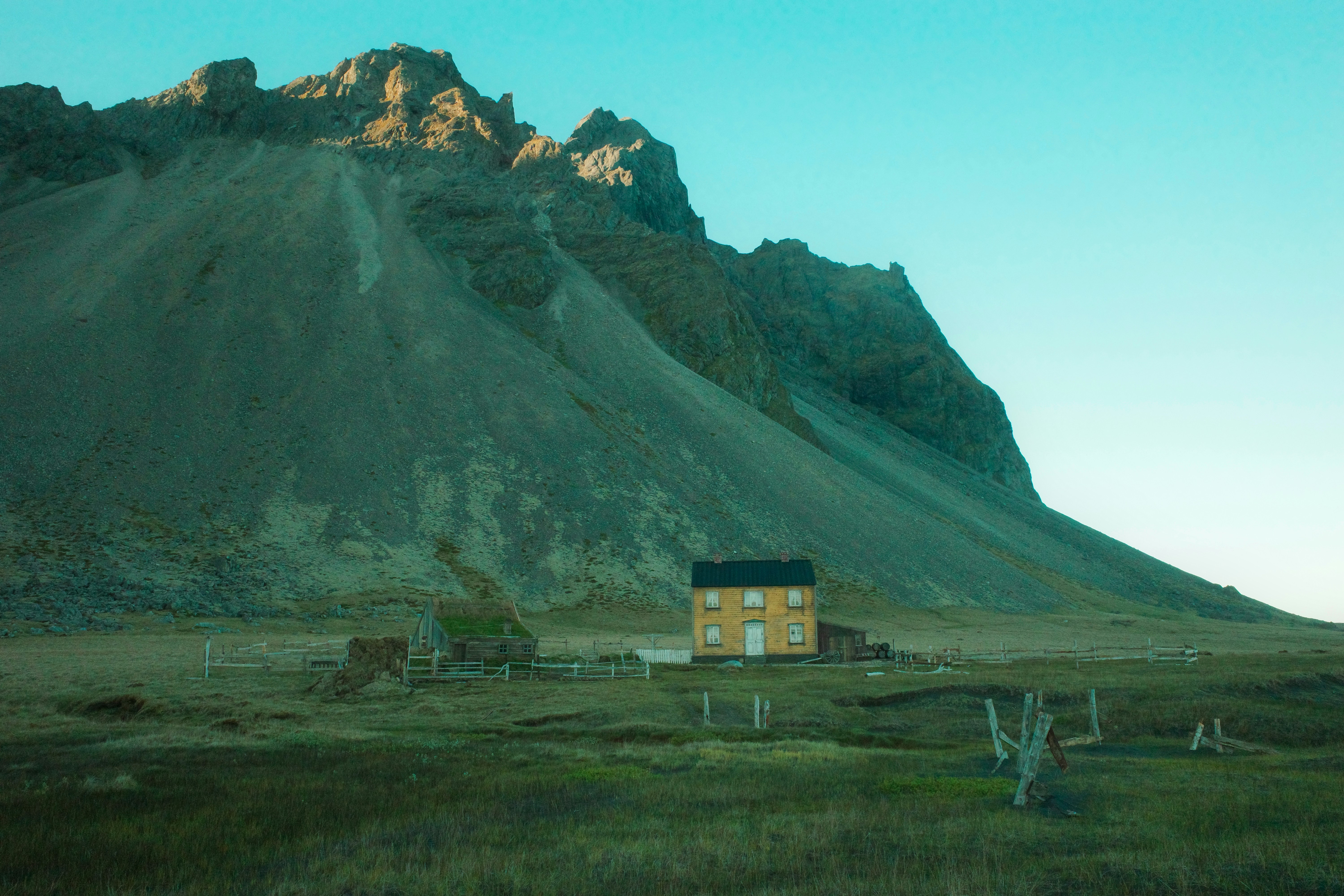 Uma casa amarela solitária fica diante de uma grande montanha.