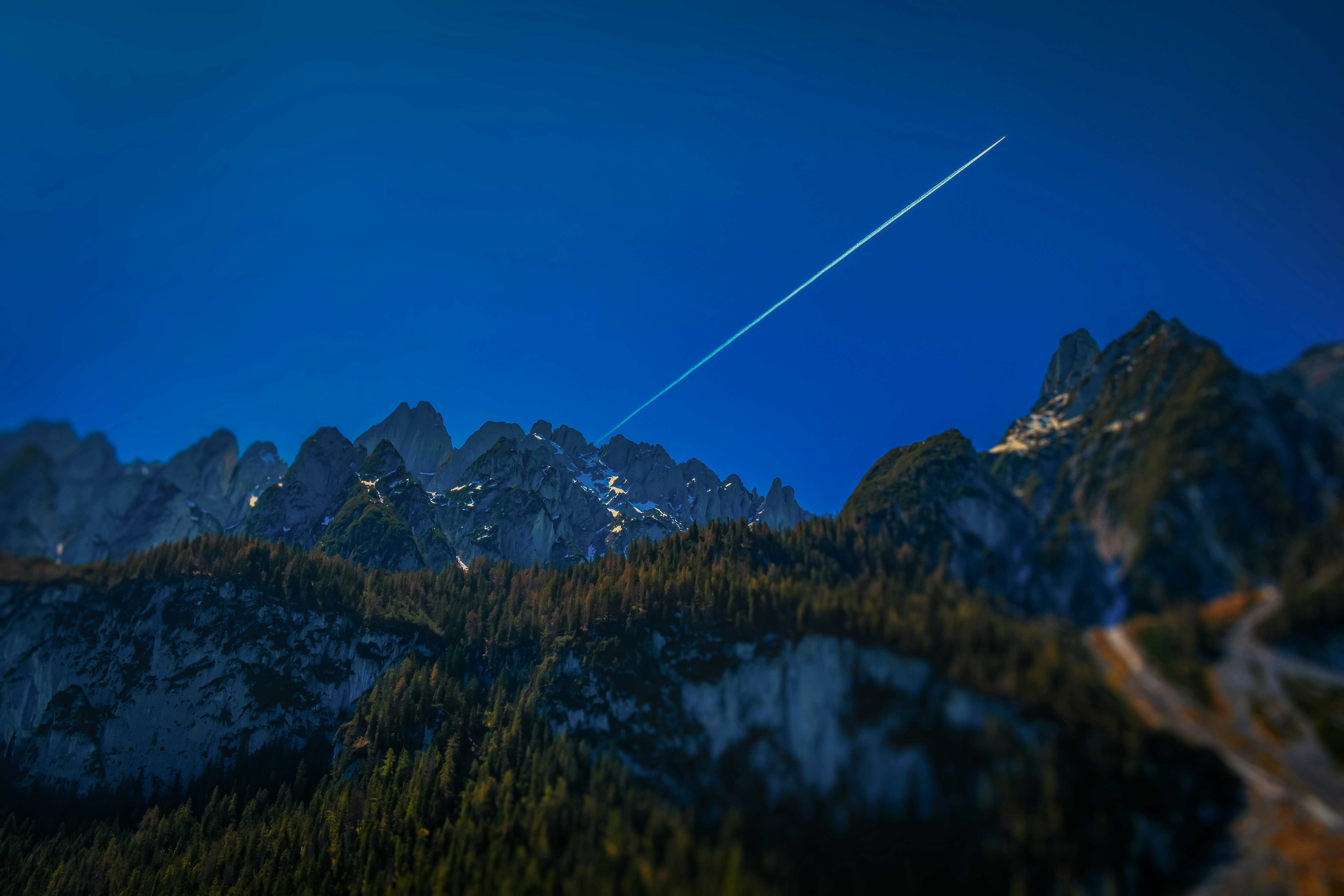 Airplane contrail over jagged mountain peaks
