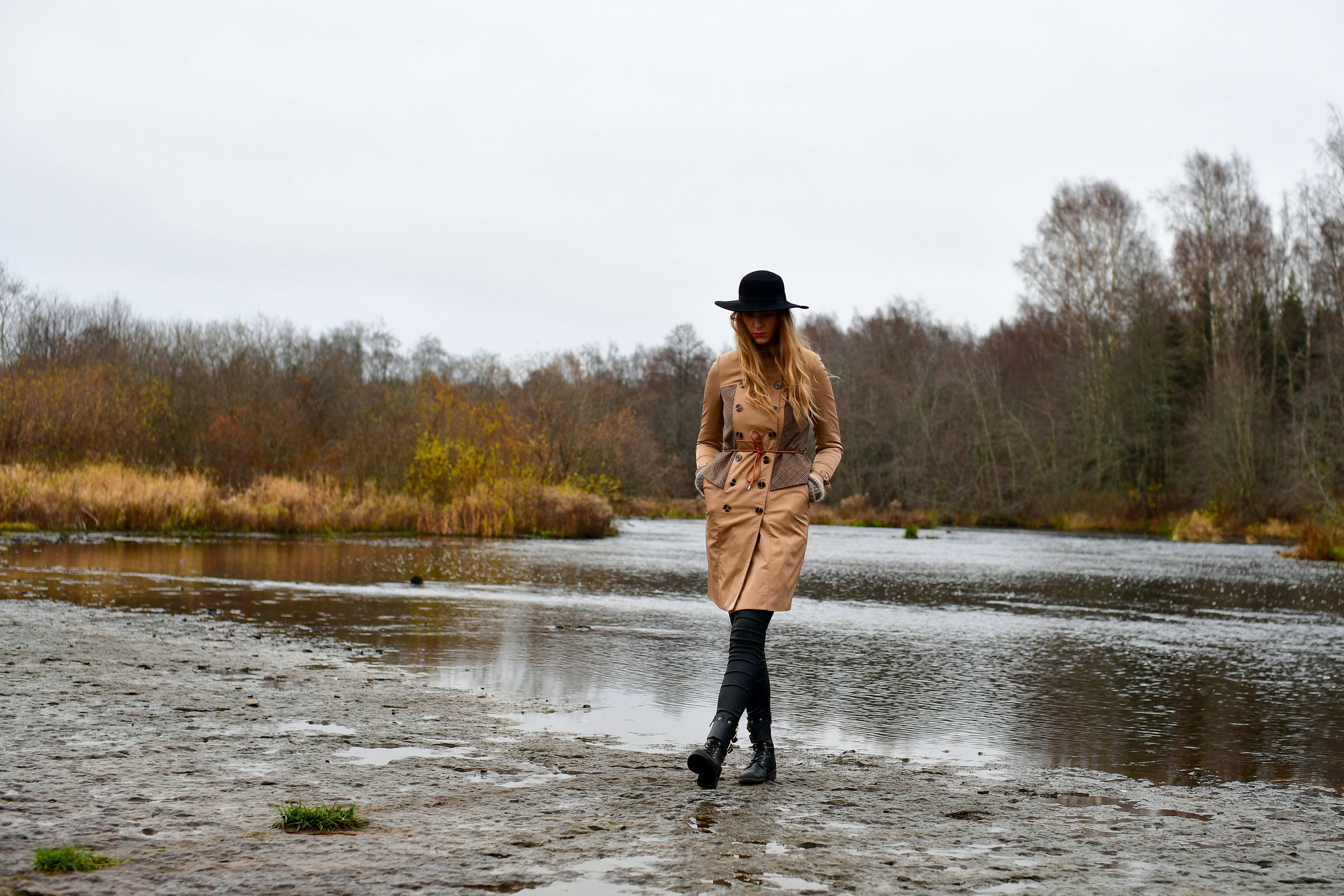 Trench coat and hat by still water, autumn