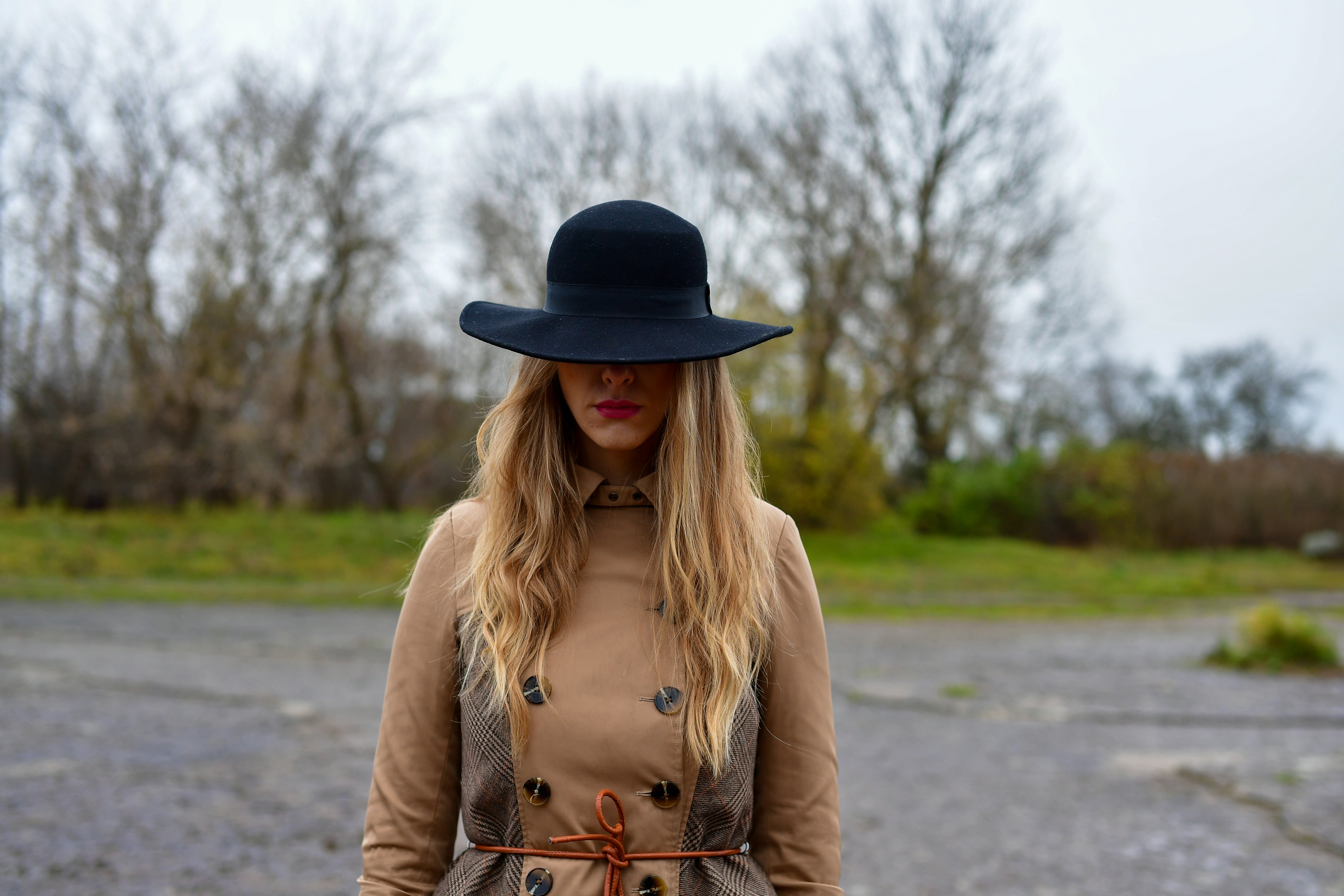 Woman in a wide-brimmed hat and coat outdoors