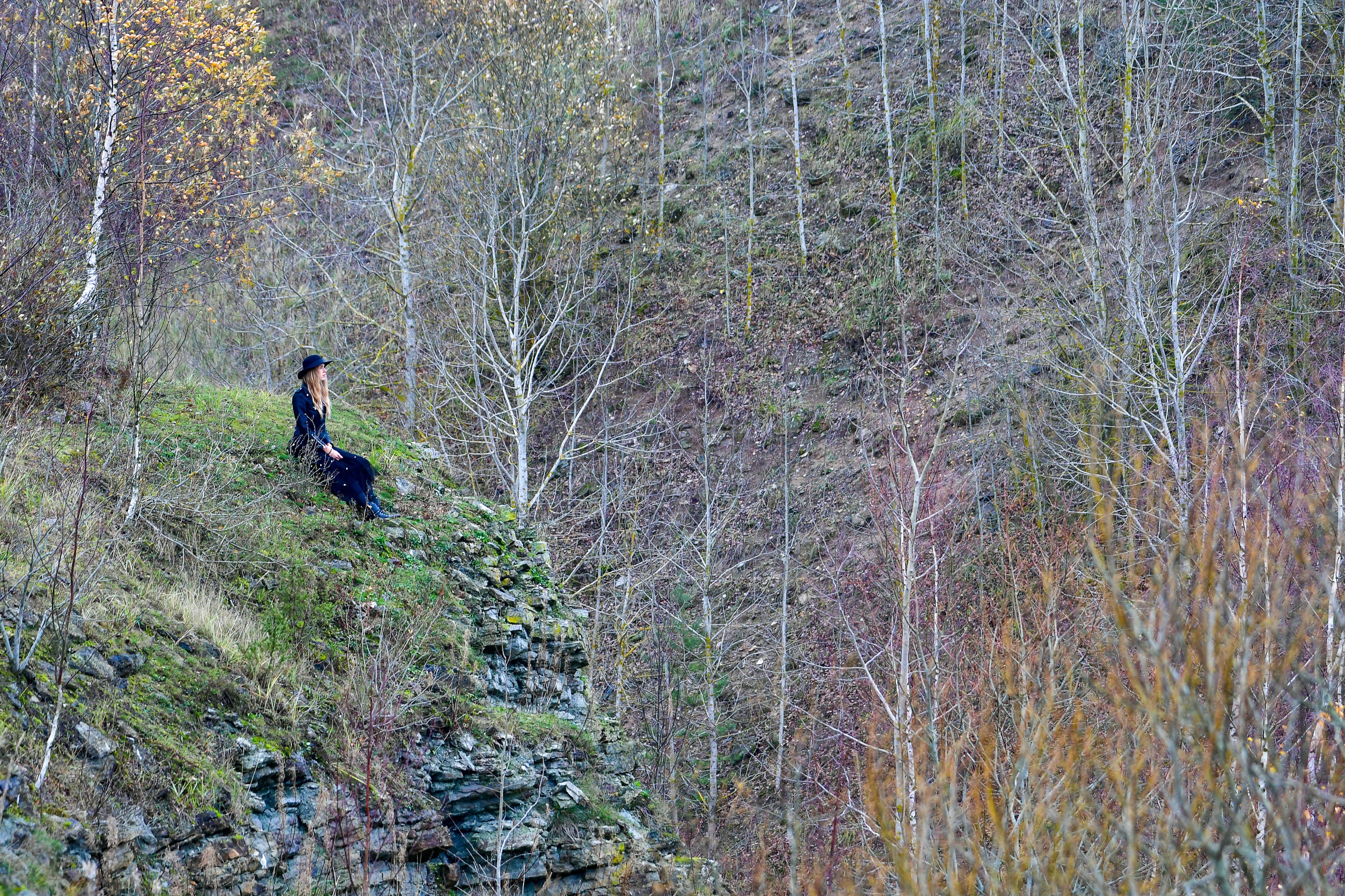 Woman sitting on a rocky cliff overlooking trees