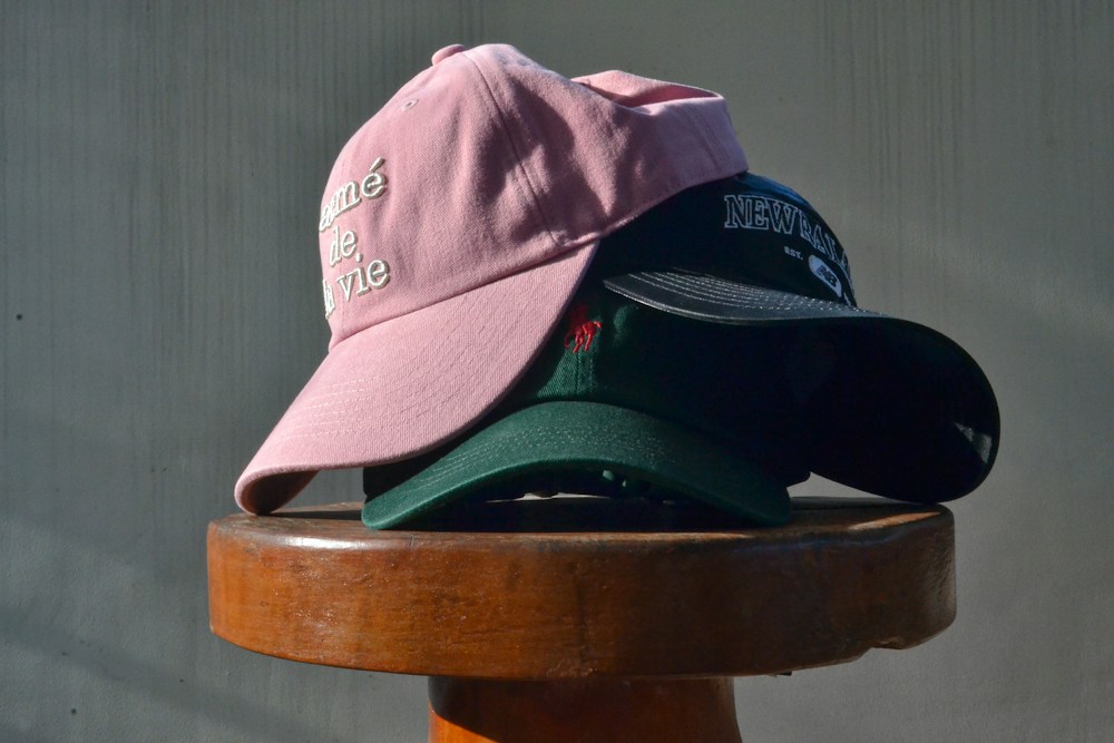 Three custom baseball caps stacked on a stool