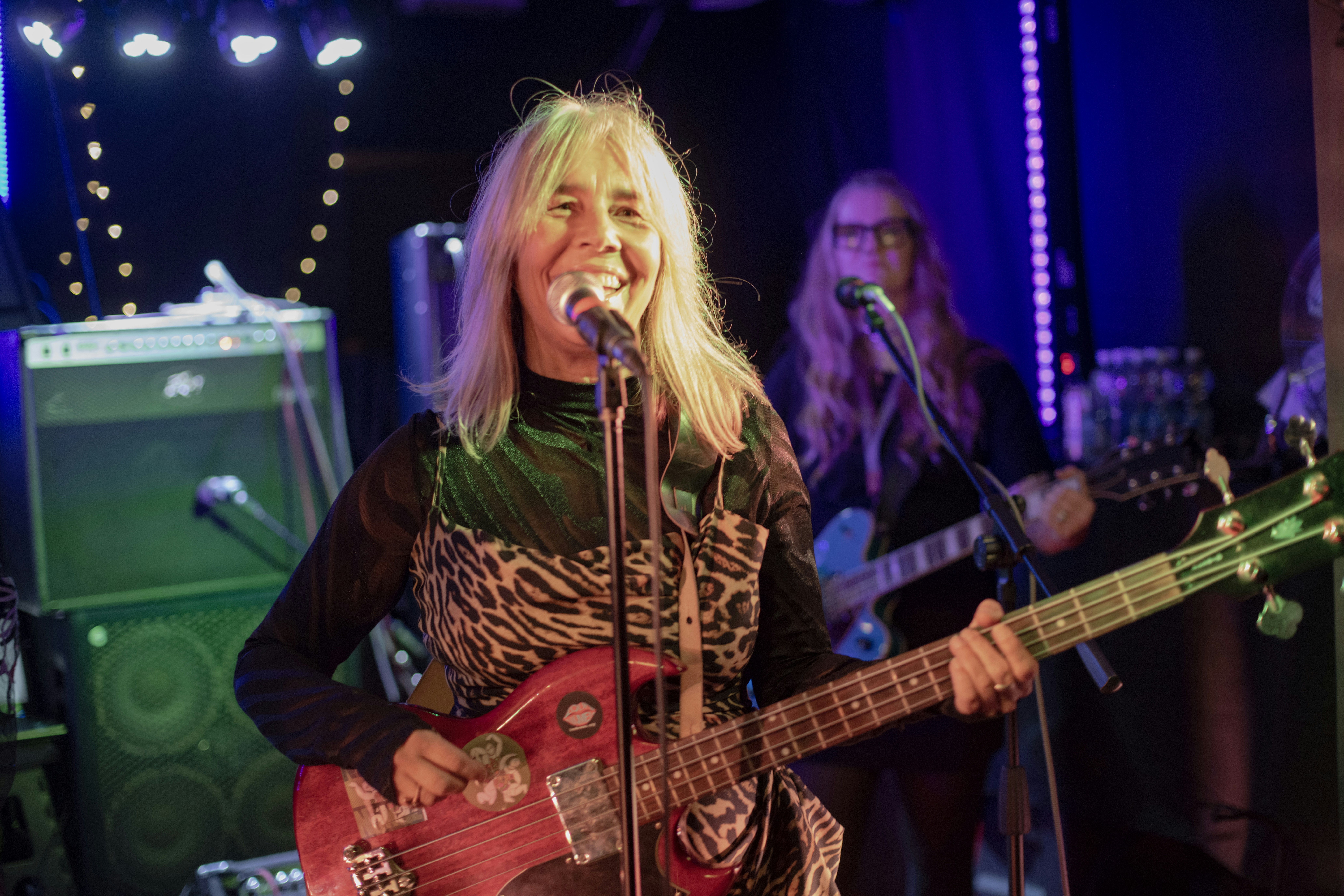 Woman playing bass guitar and singing on stage