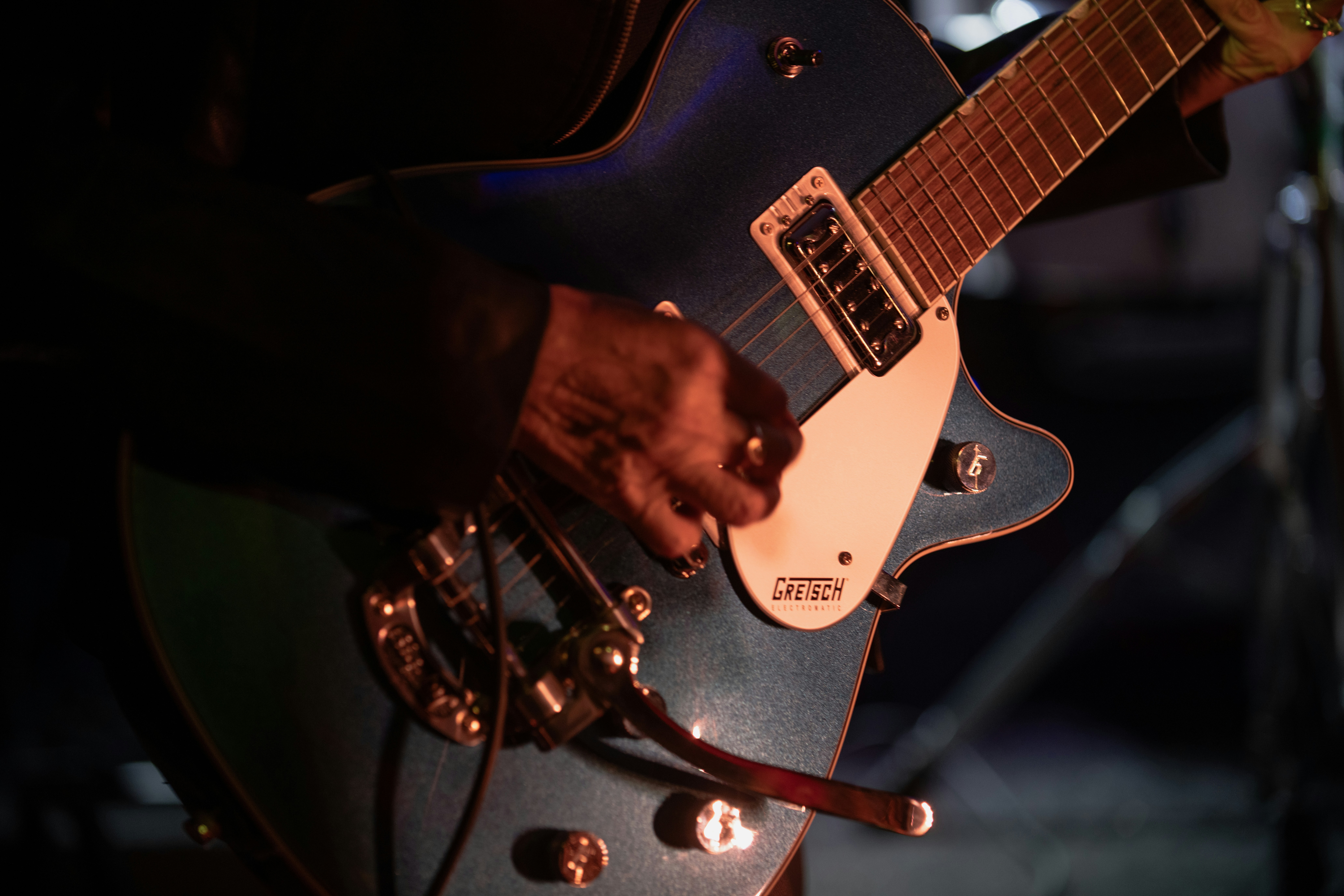 A person playing a blue electric guitar