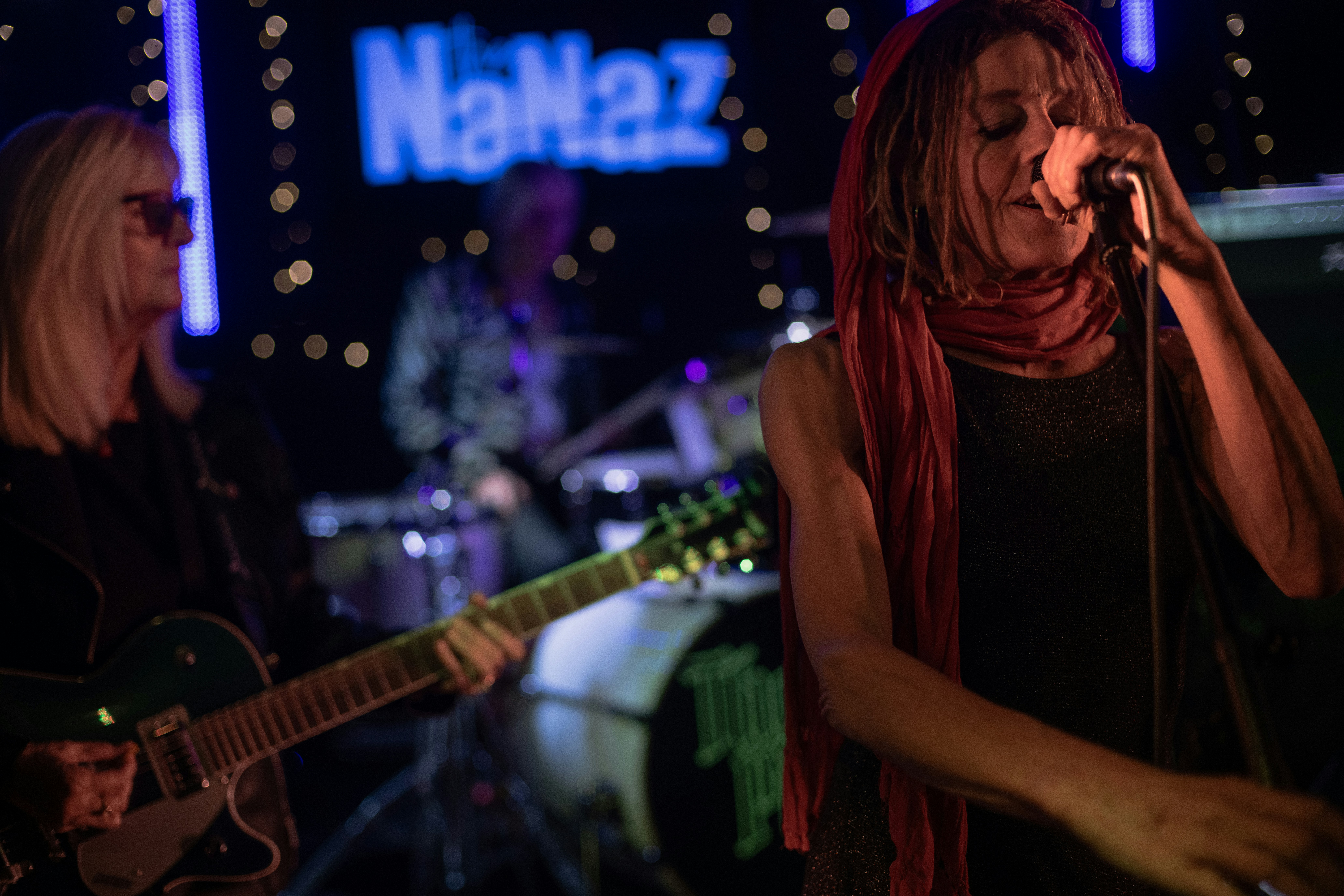 Woman singing into microphone on stage with band