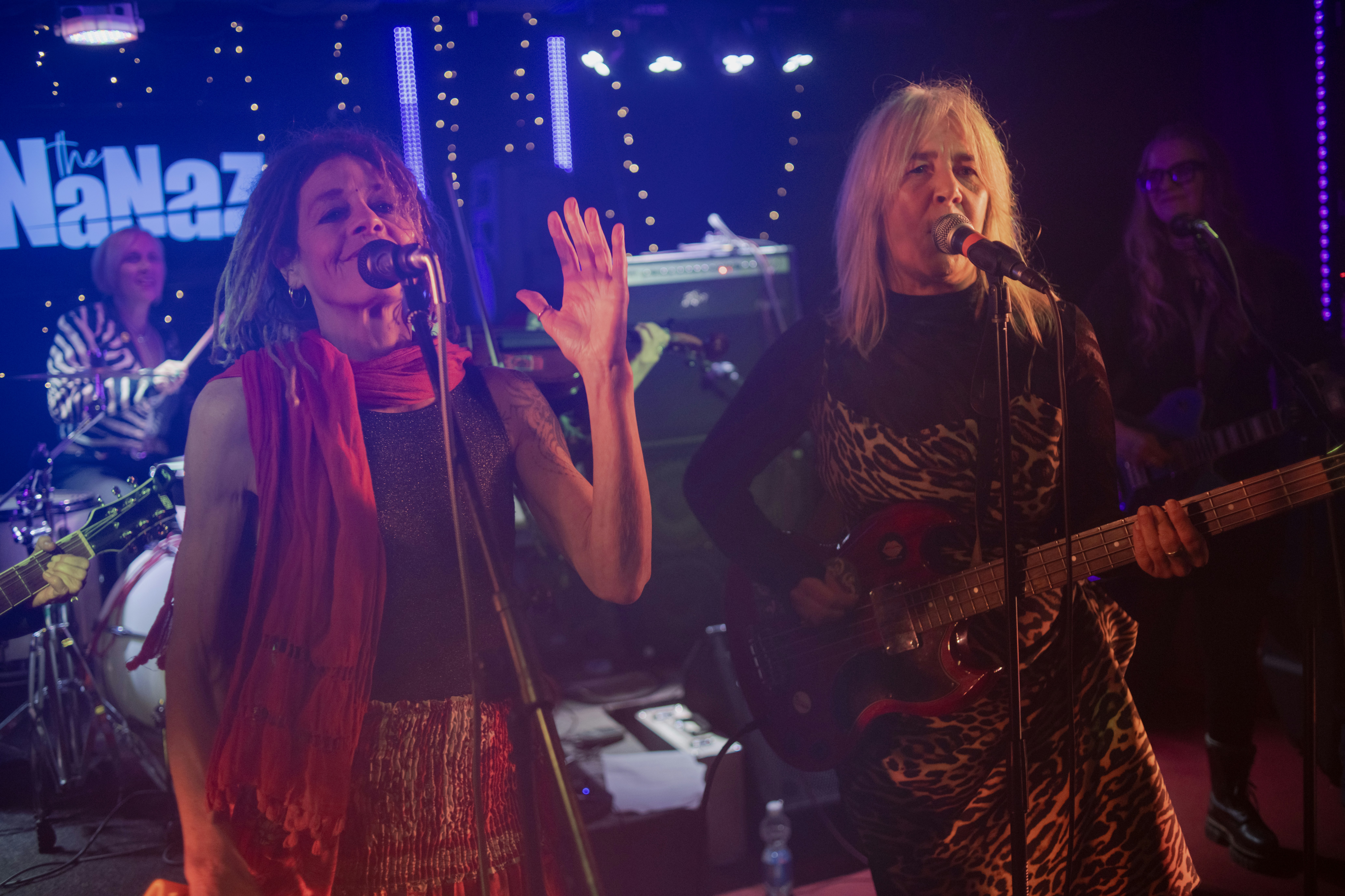 Two women singing and playing guitar on stage.