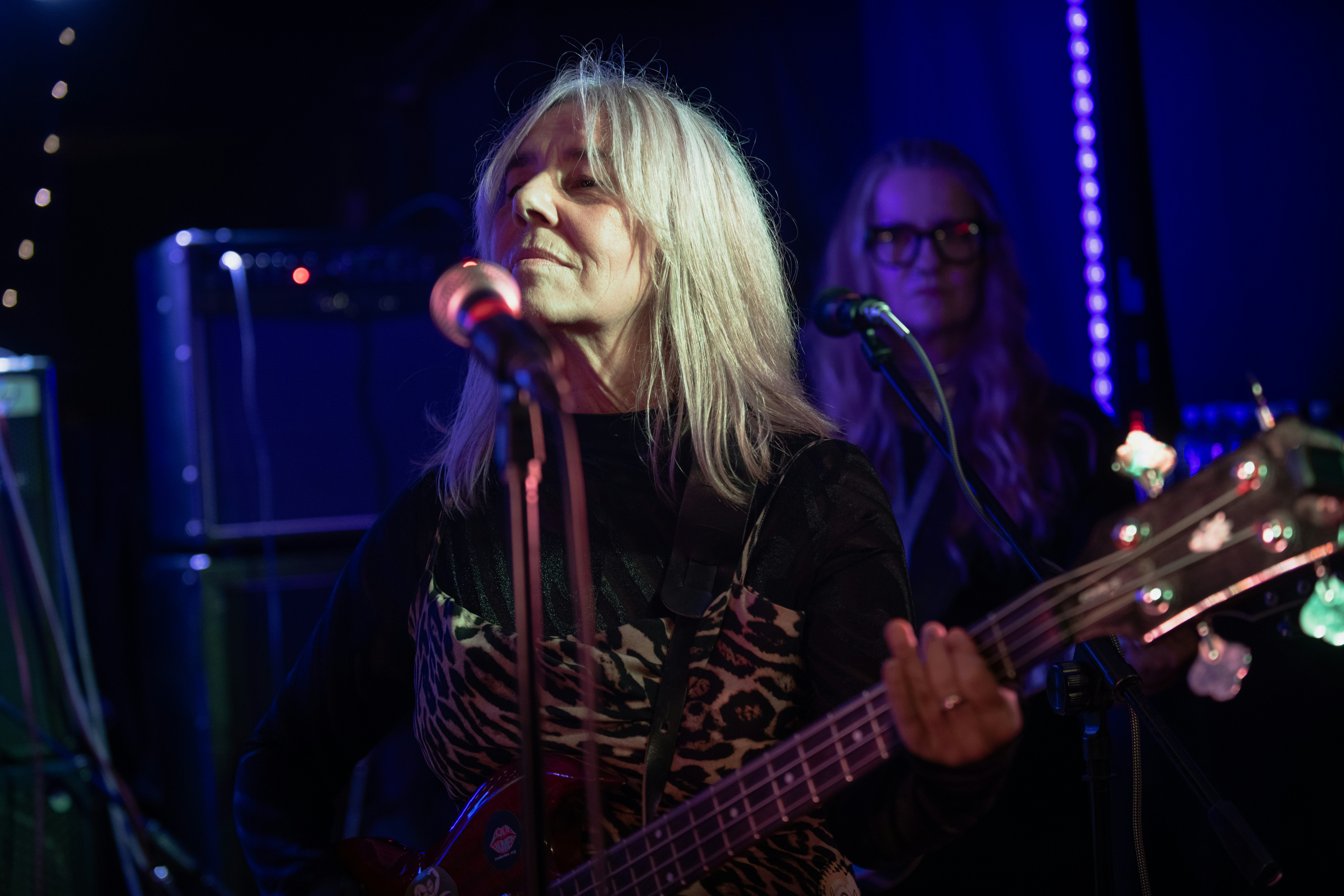 Woman singing and playing bass guitar on stage