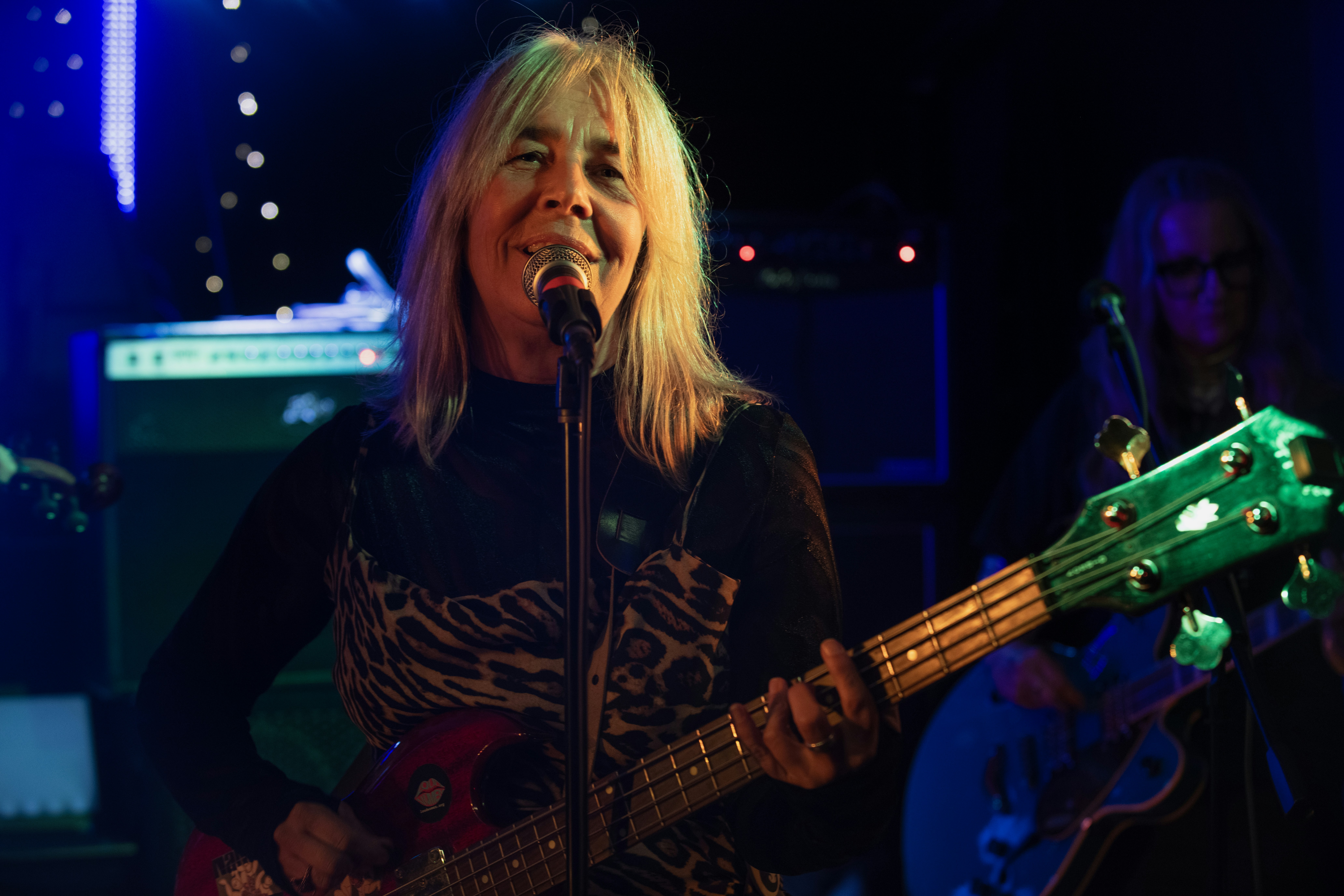 A woman playing bass guitar on stage at a concert.