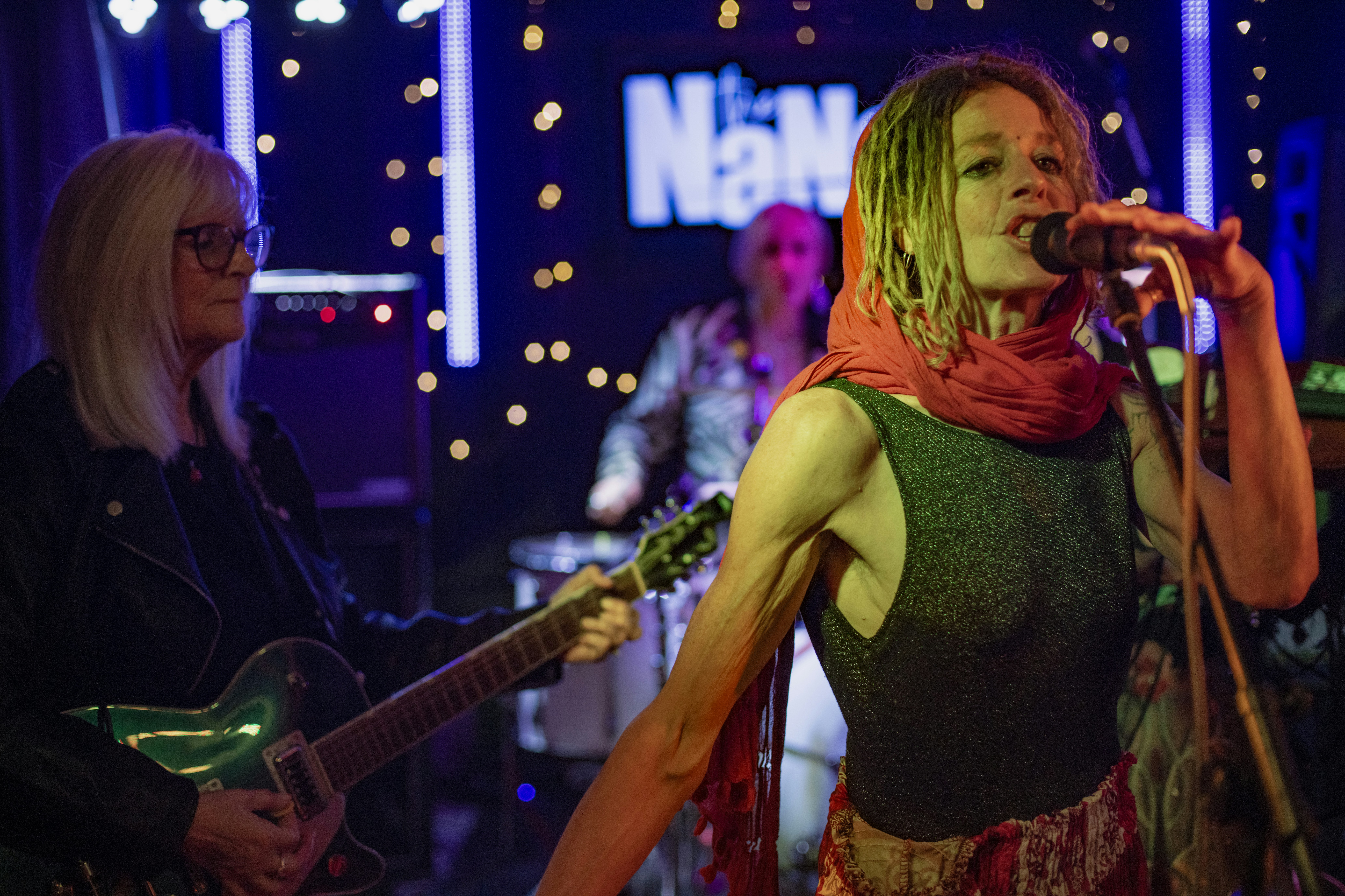 Woman singing into microphone on stage with band