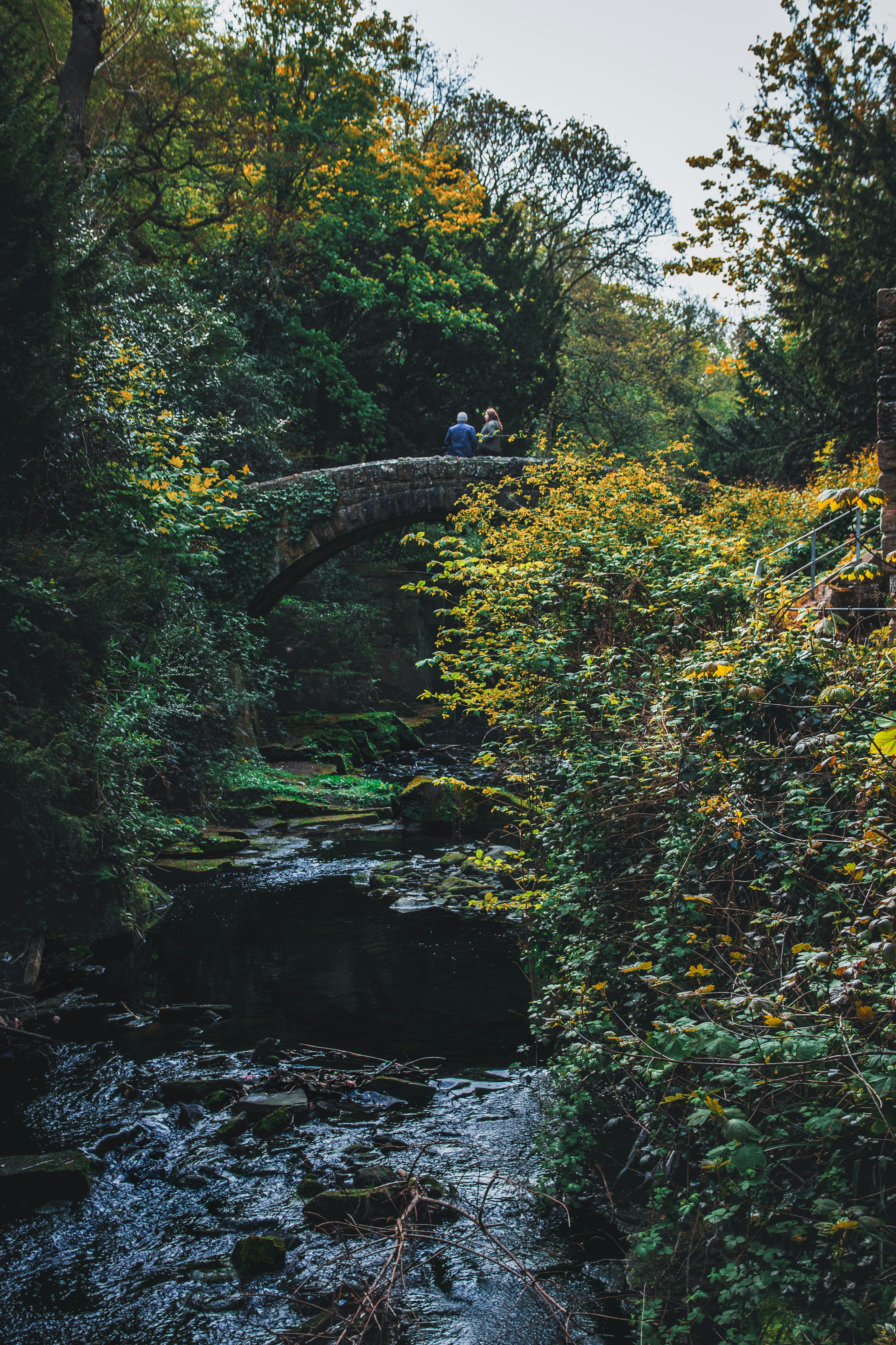 Dos personas en un puente de piedra sobre un arroyo.