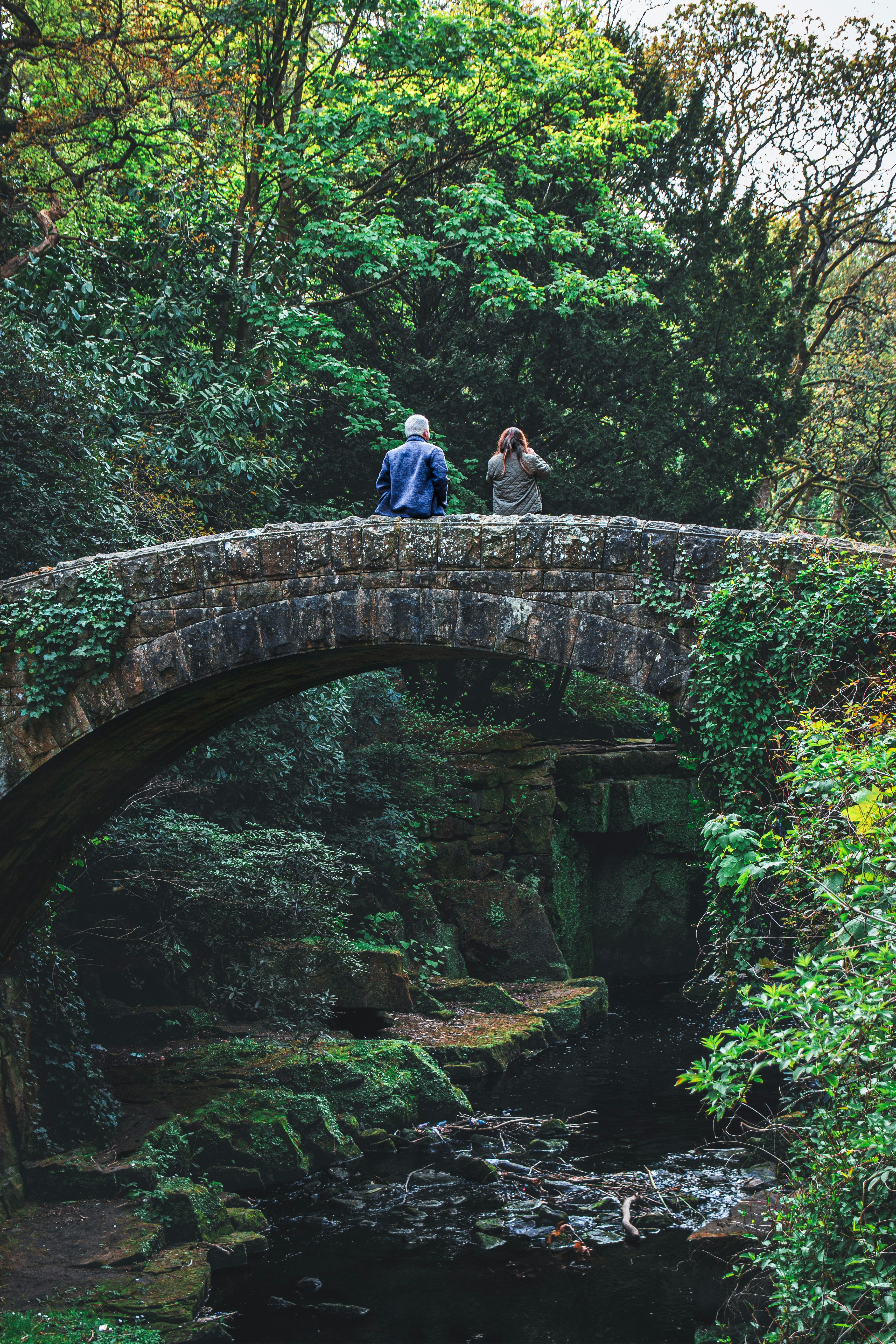Dos personas sentadas en un viejo puente de piedra