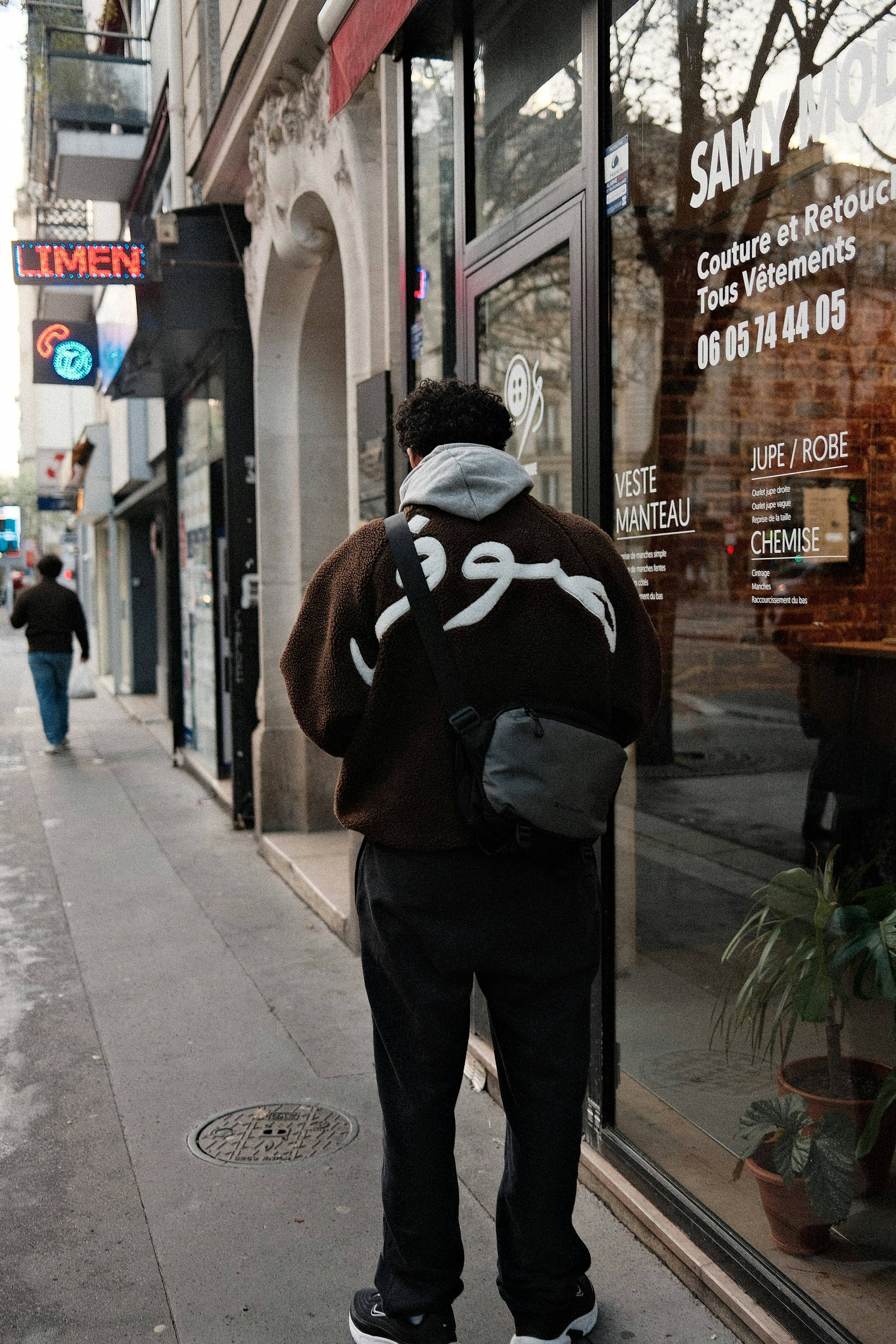 Un homme en sweat à capuche marche dans une rue de la ville.