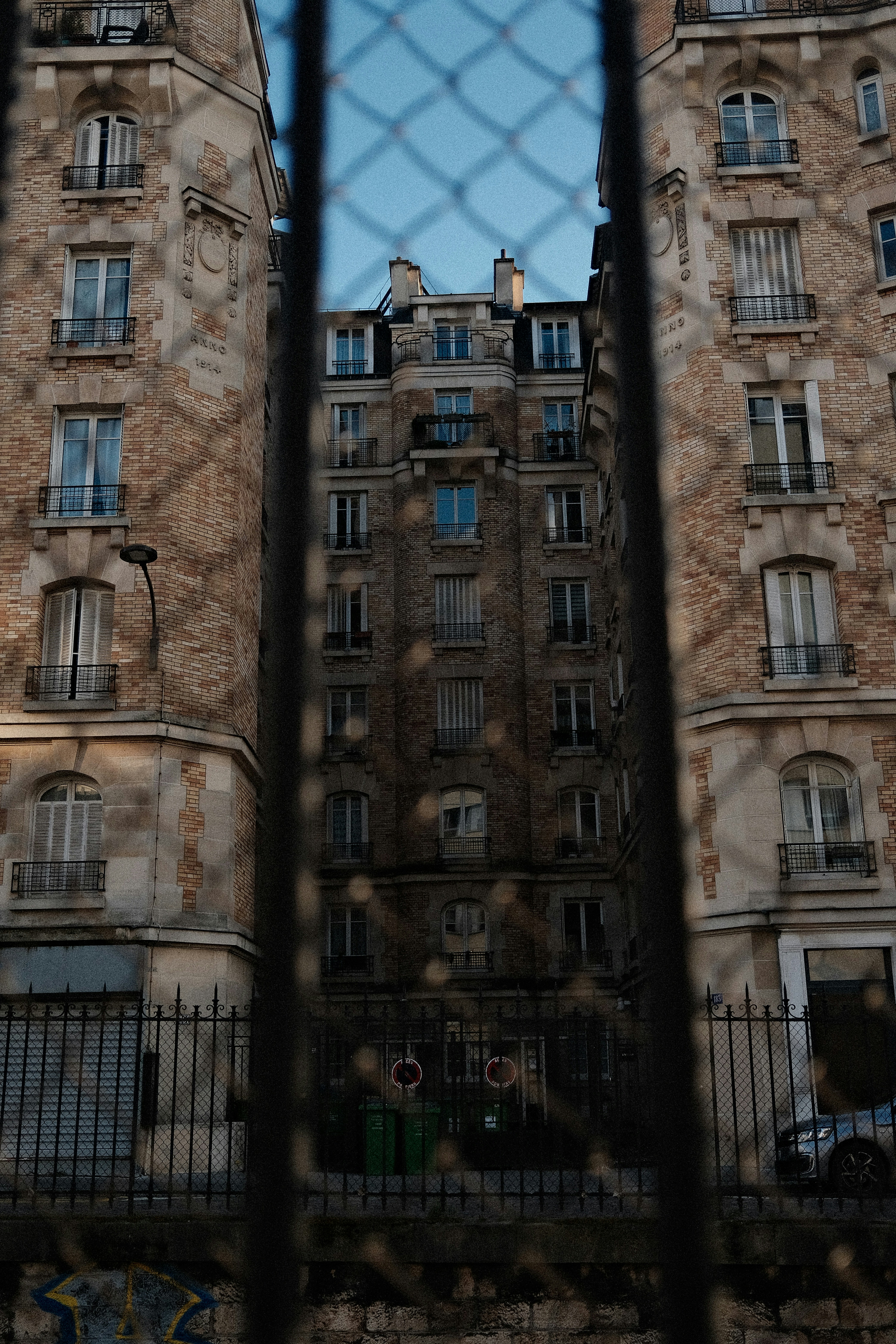 De vieux immeubles d’appartements vus à travers une clôture.