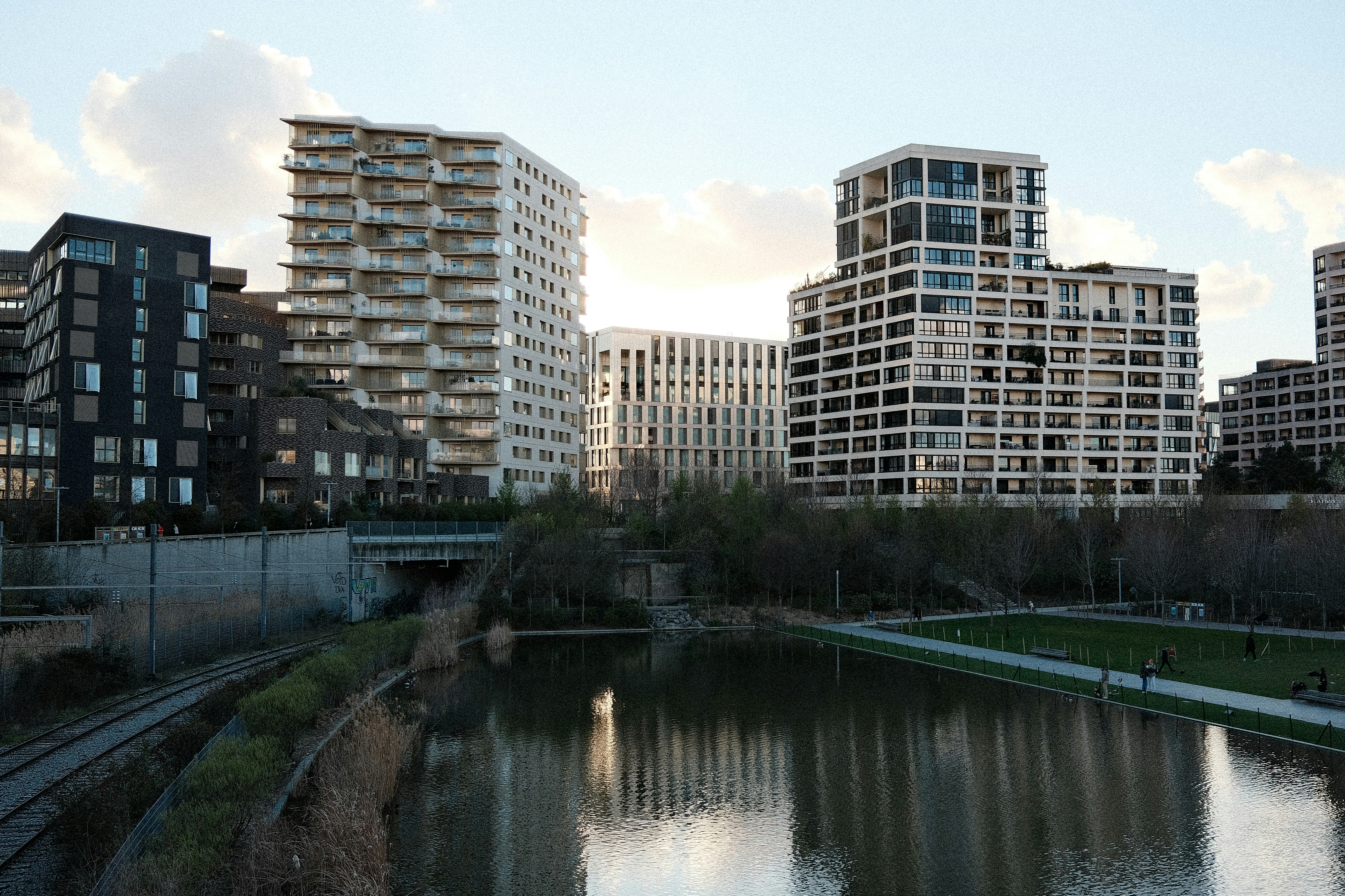 Modern buildings line a canal with reflections.