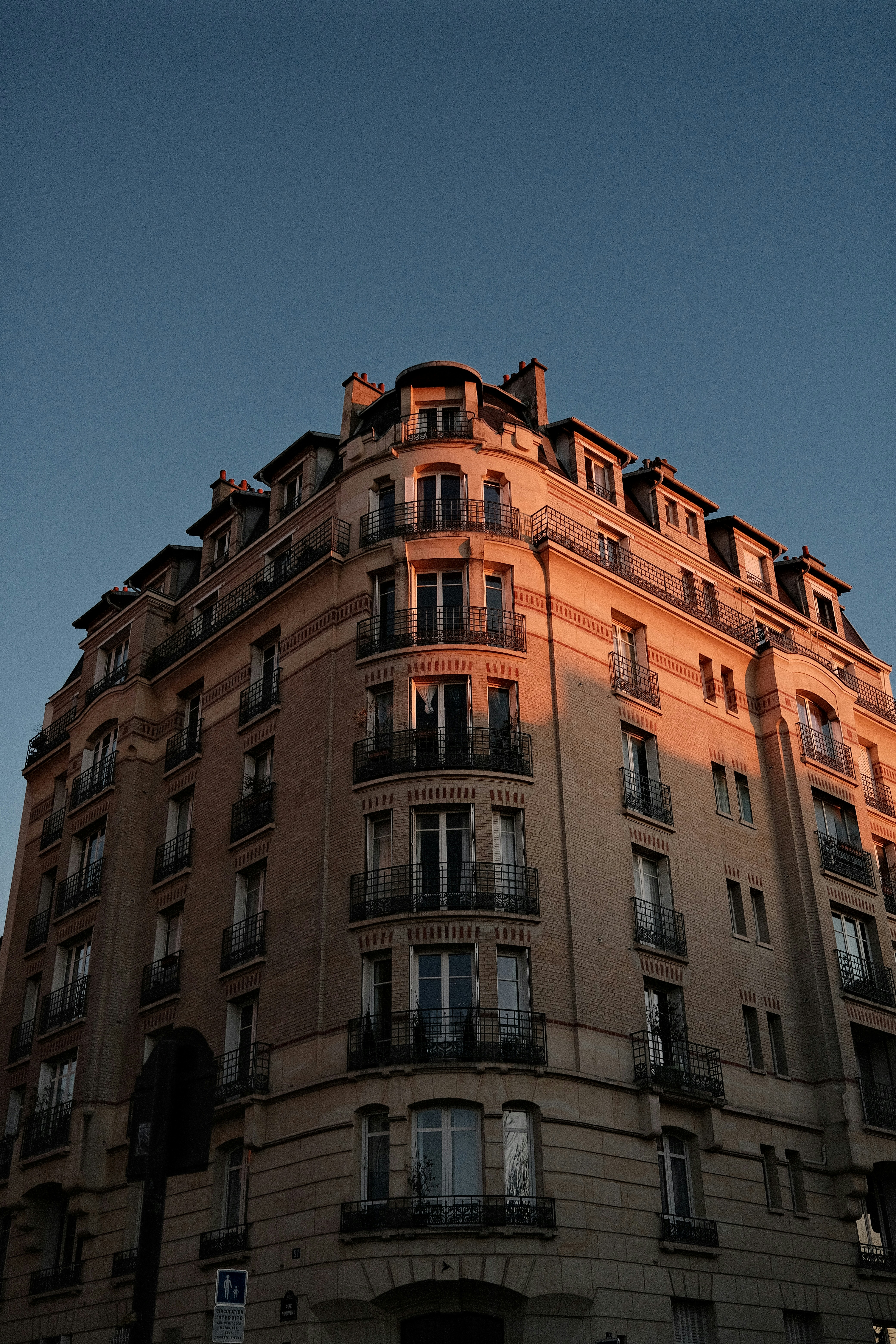 Un bâtiment parisien orné baigné d’une lumière chaude du coucher de soleil.