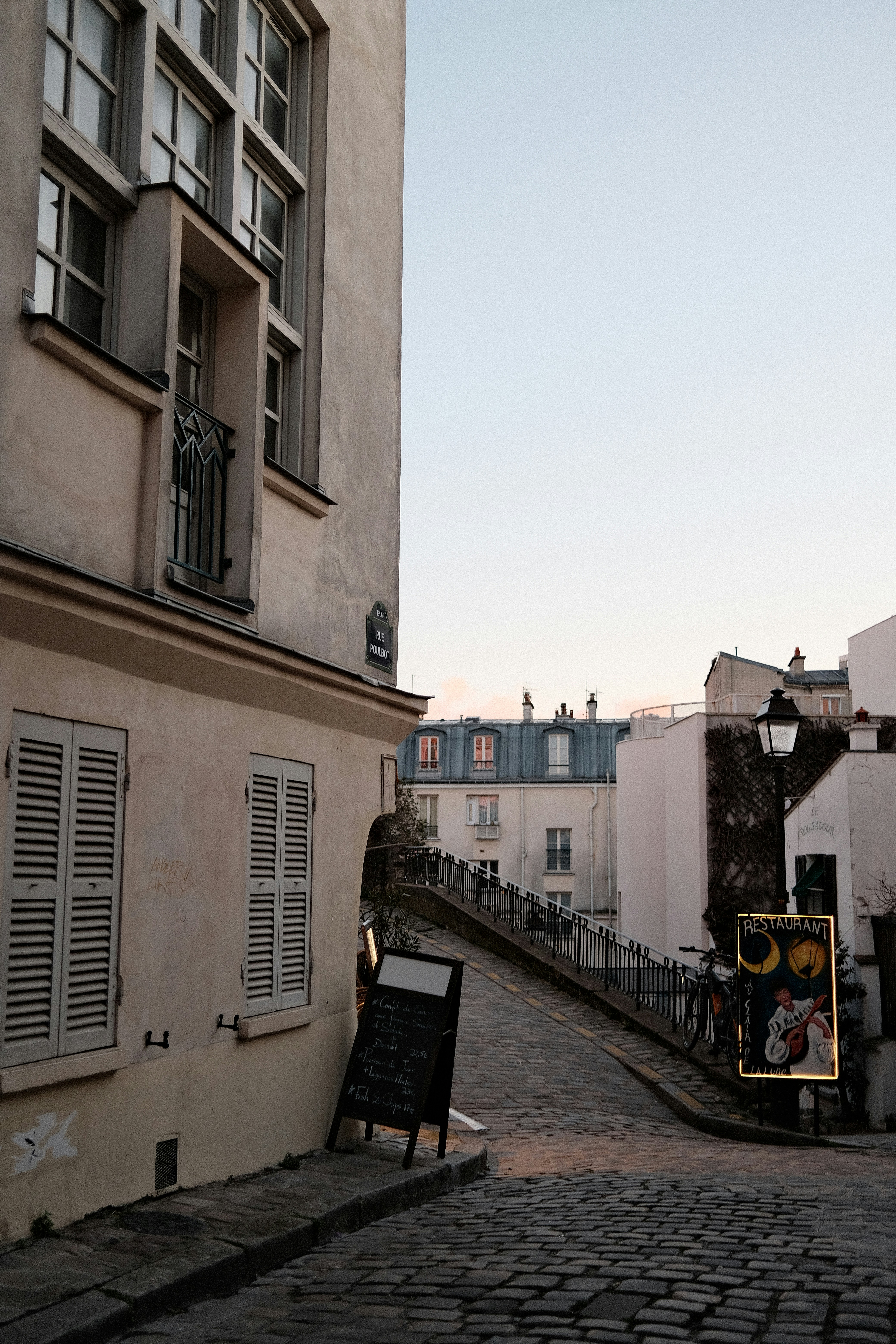 Rue pavée avec bâtiments et enseignes à Paris.
