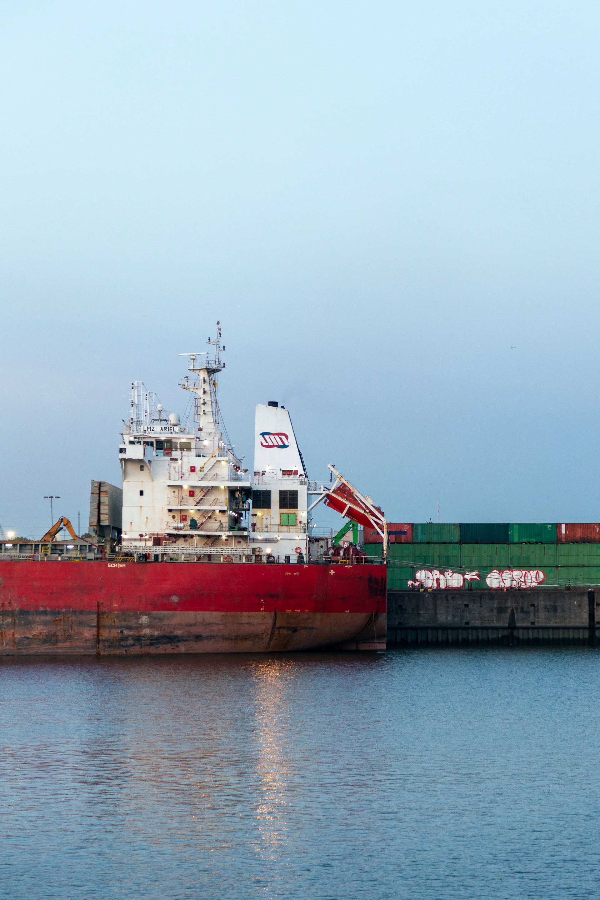 A large red cargo ship docked at a pier