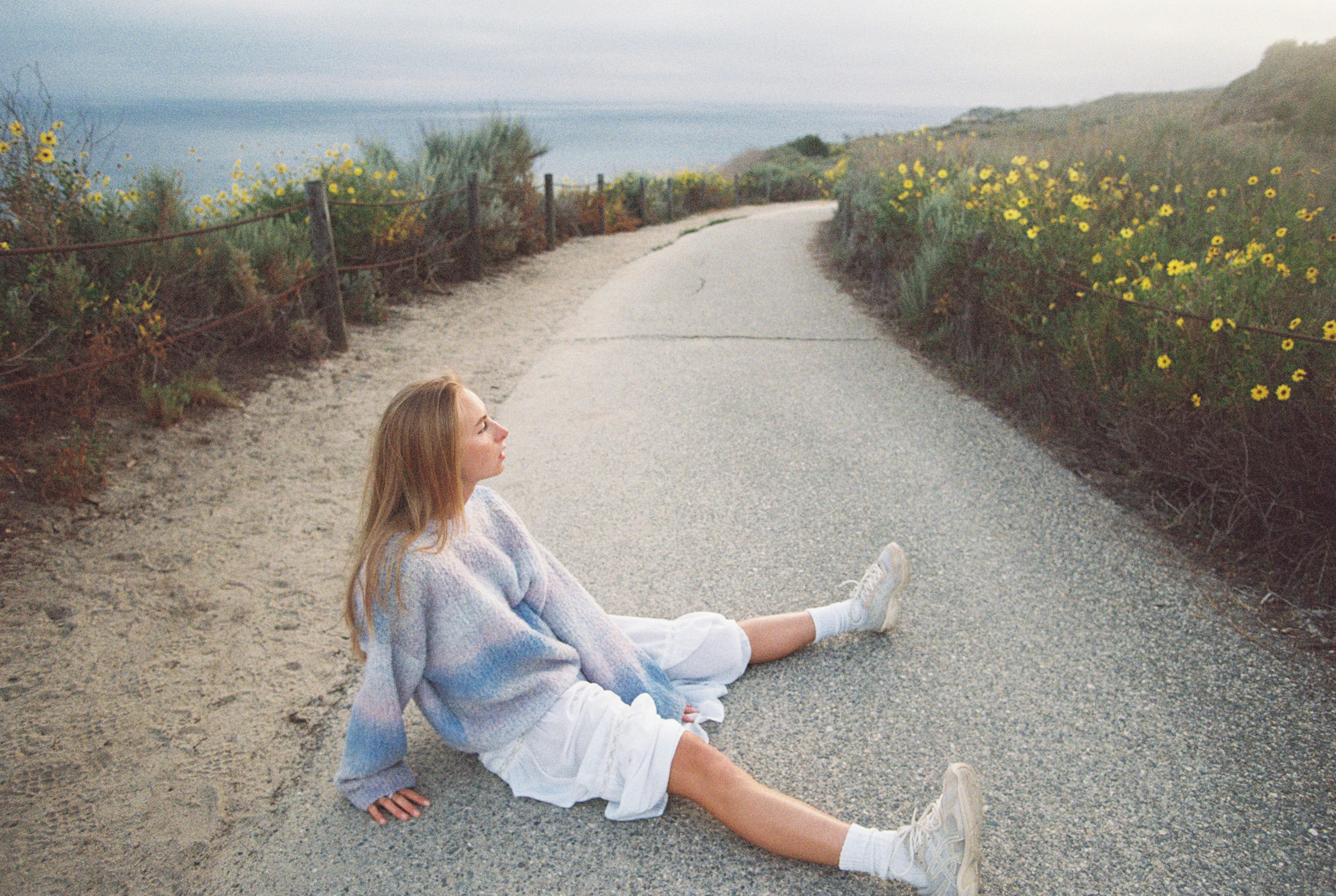 海を見下ろす道路に座る若い女性