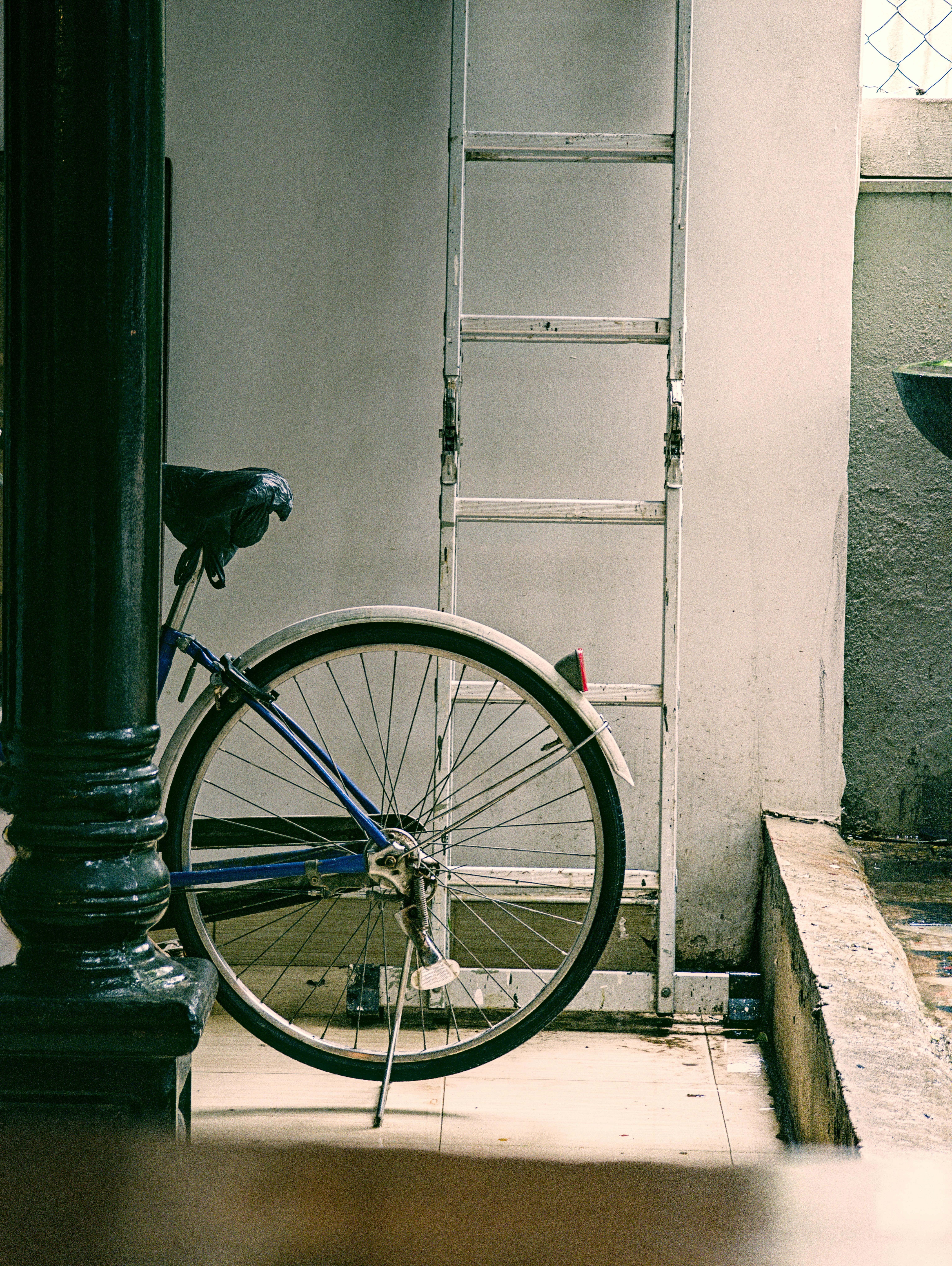 Una bicicleta se apoya en una pared con una escalera.