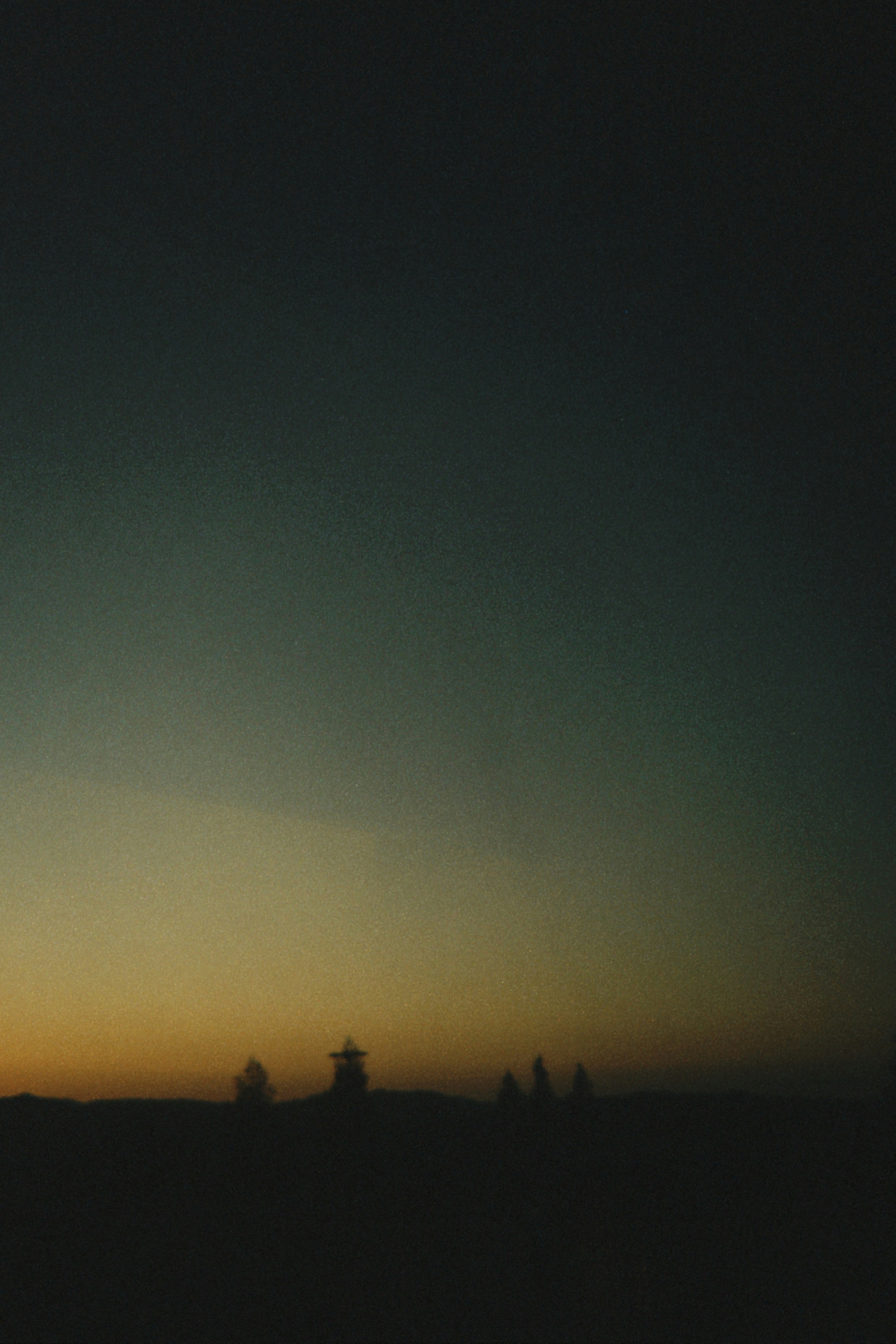 Silhouette of a windmill and figures against a sunset sky.