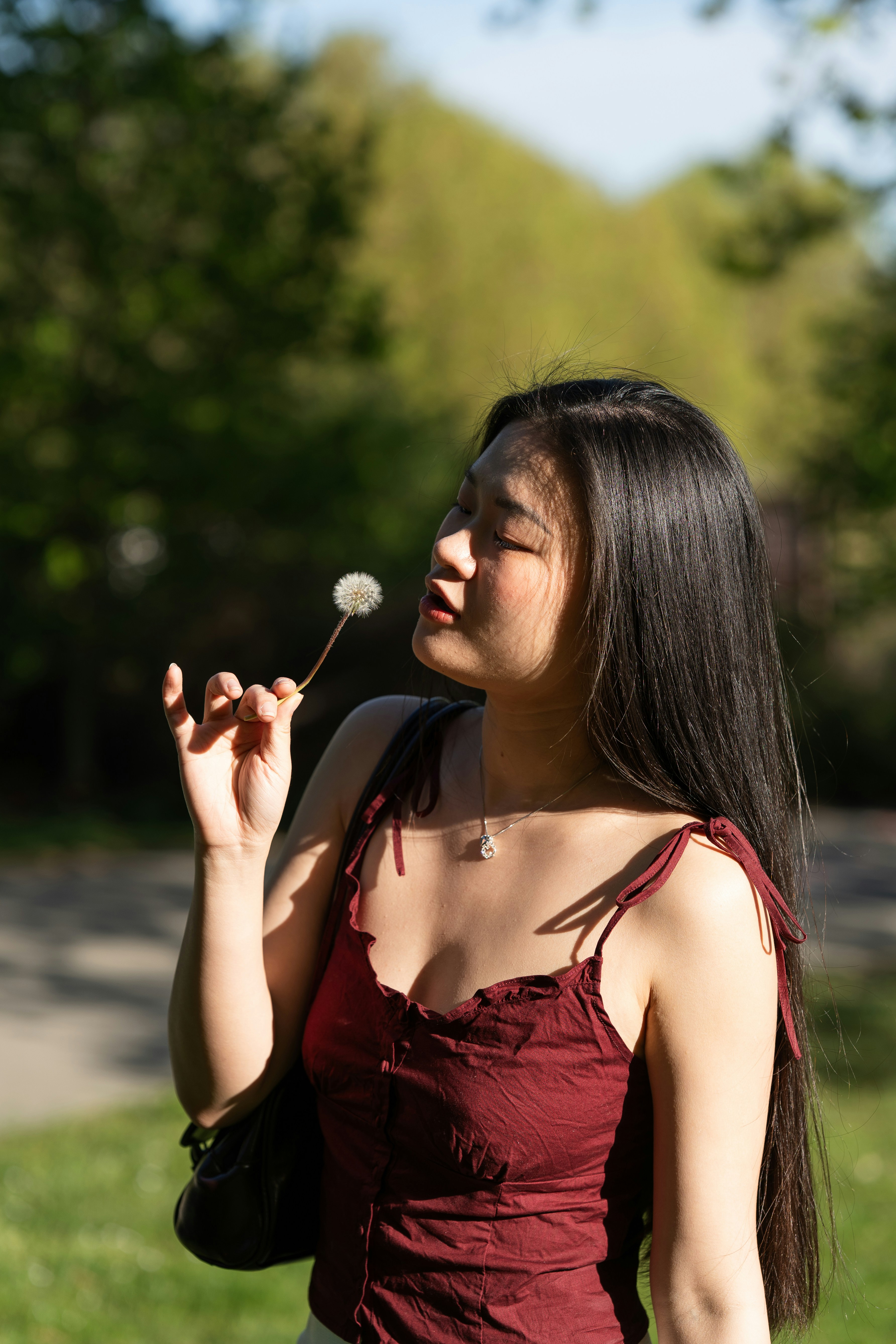 Wanita muda memegang dandelion di taman.