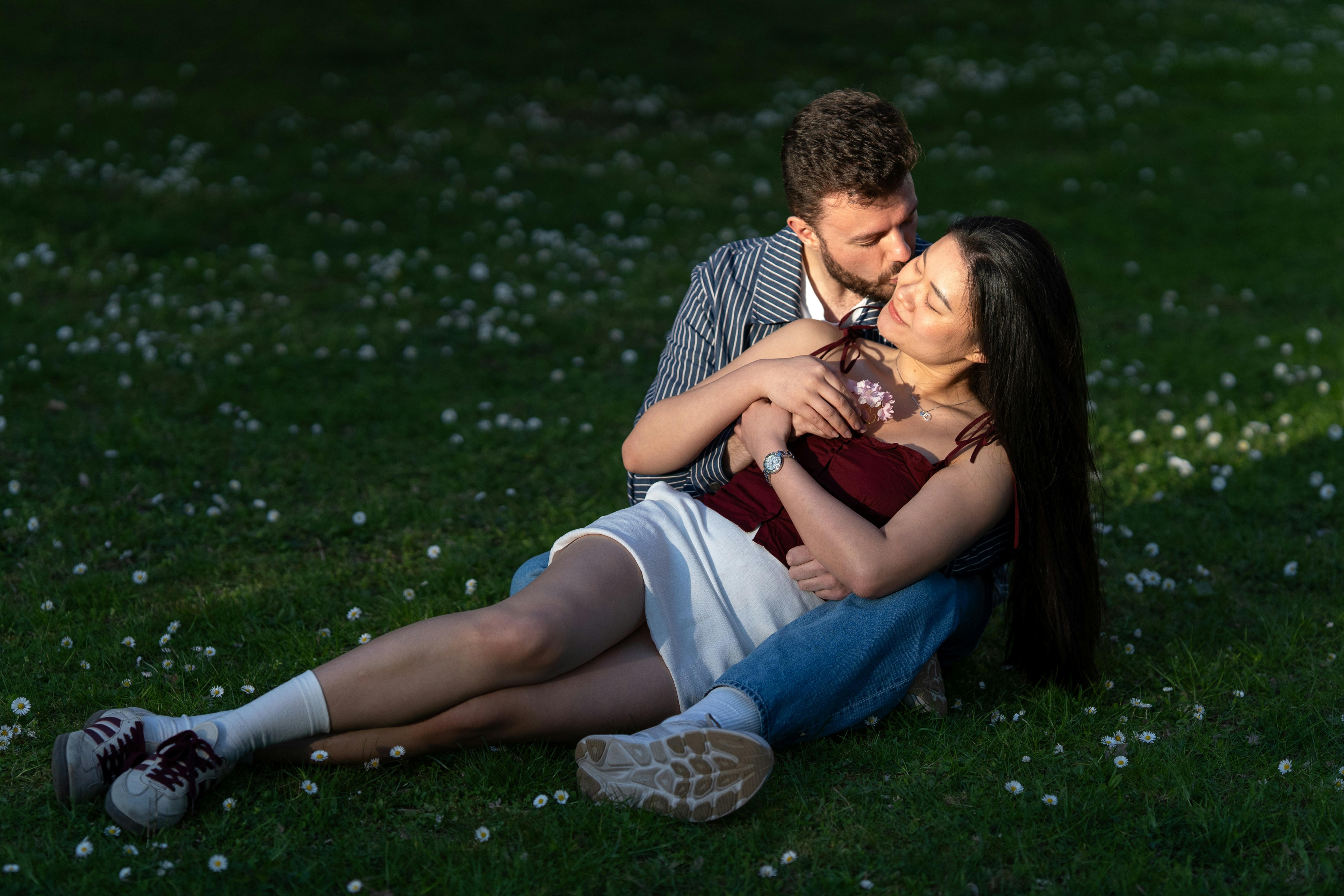 Couple embracing on a grassy field with flowers