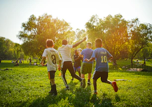 Children playing soccer in a sunny park