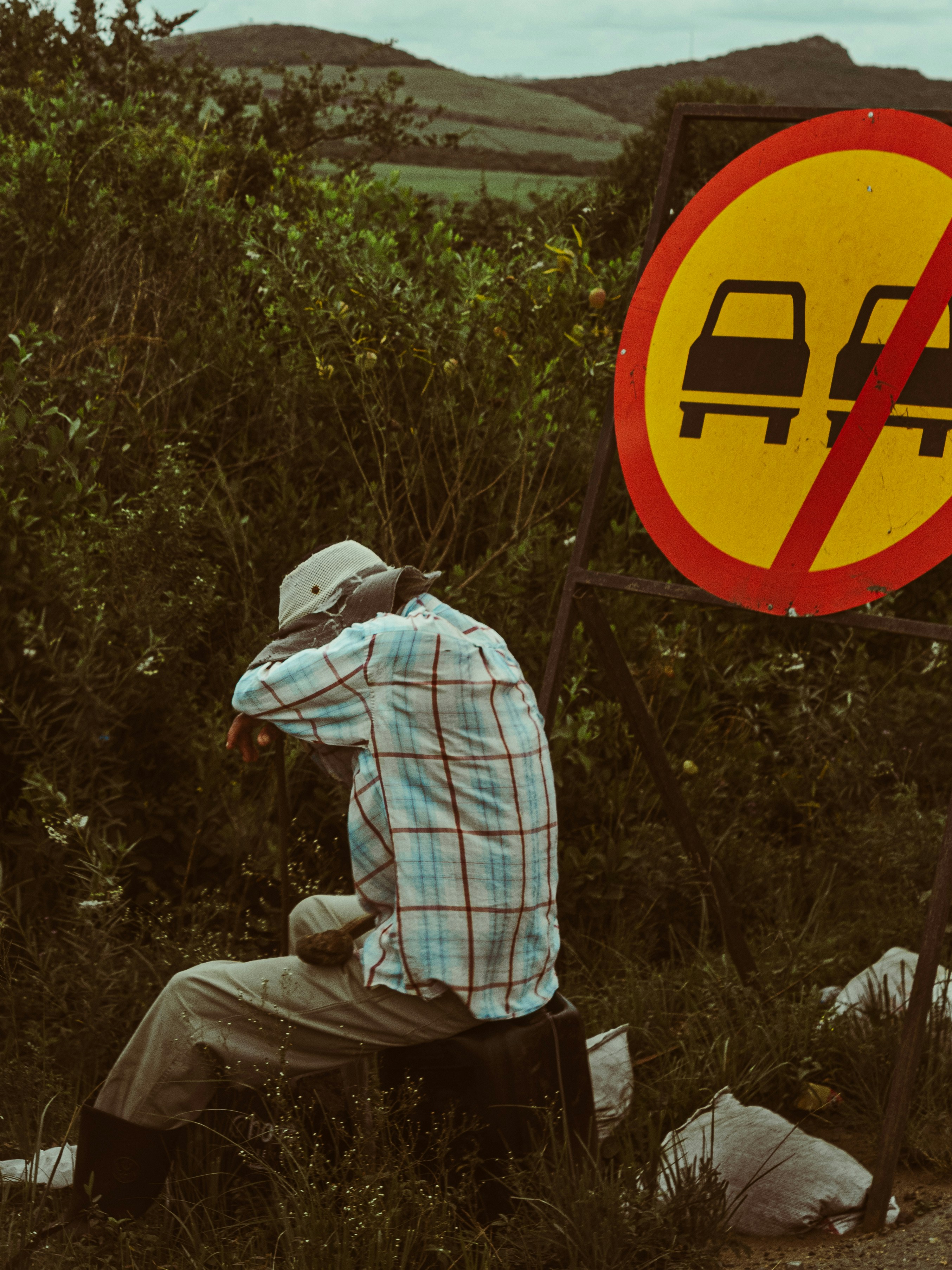 Man in hat rests by no passing sign - roadside historical markers