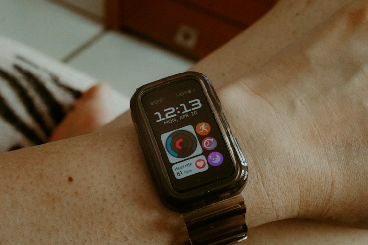 Woman checking a fitness wearable device on her wrist while reviewing health data on her phone