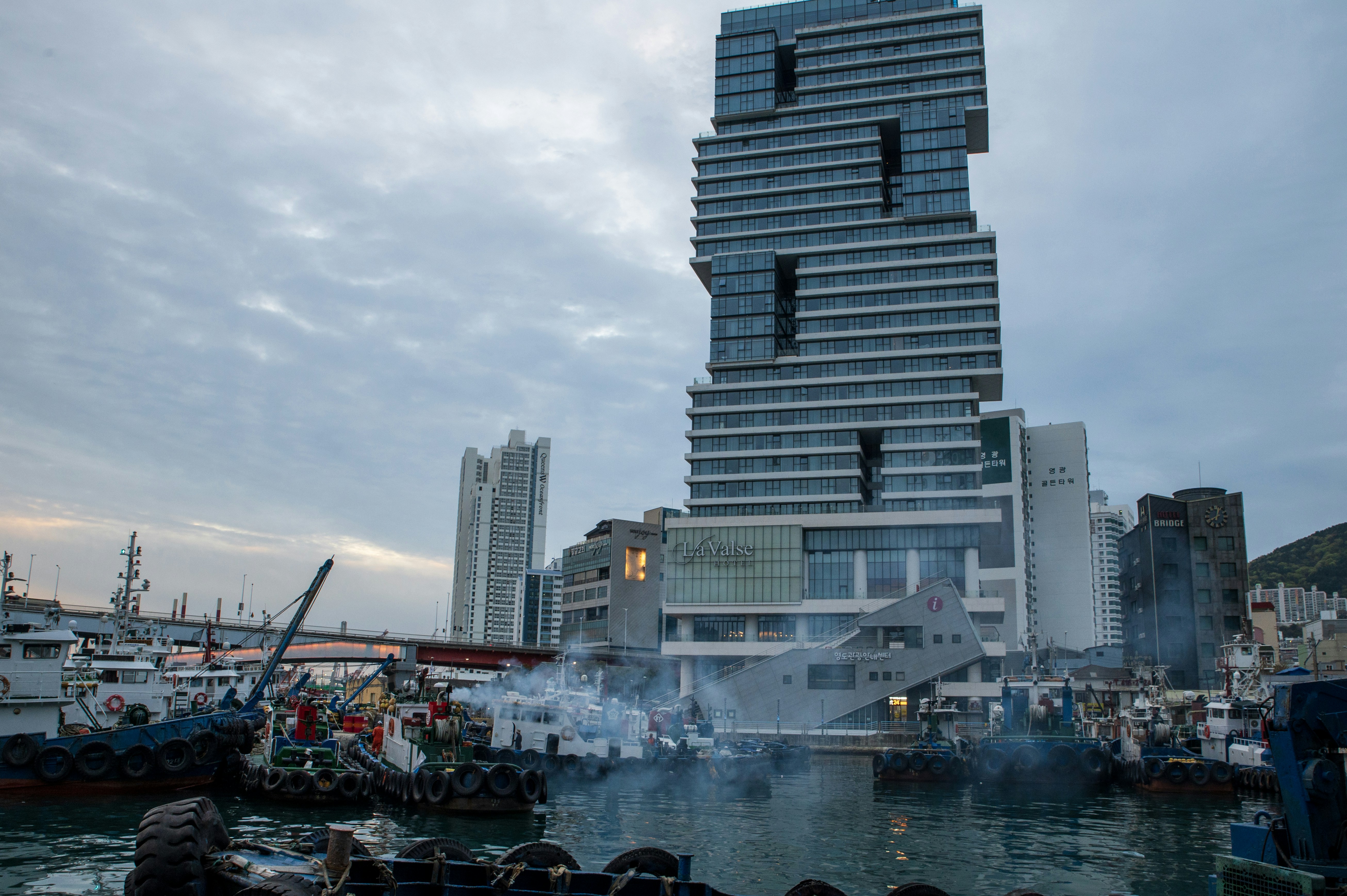 Modern building overlooking a busy harbor with boats