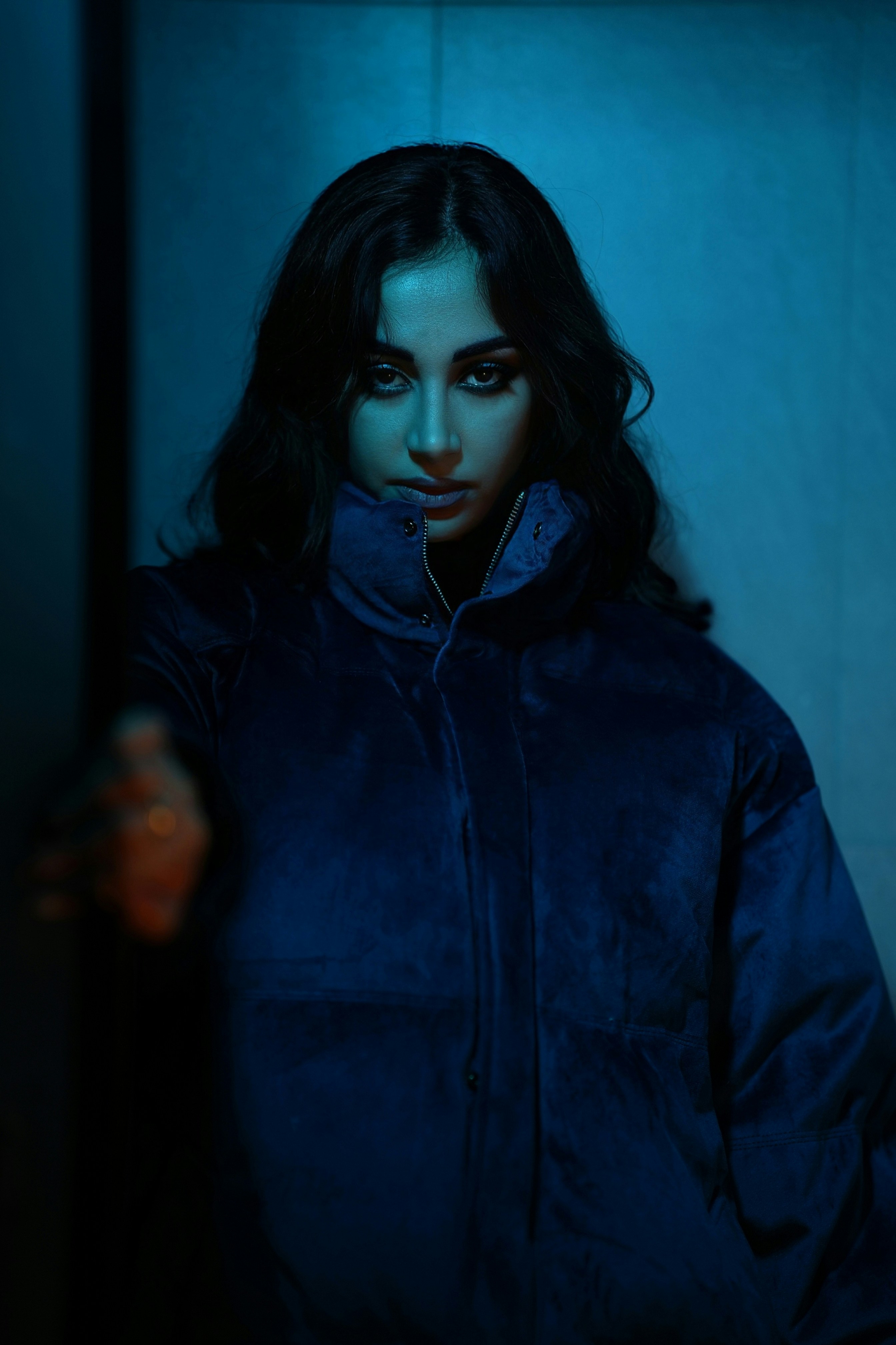 Seorang wanita berjaket biru mengulurkan tangan