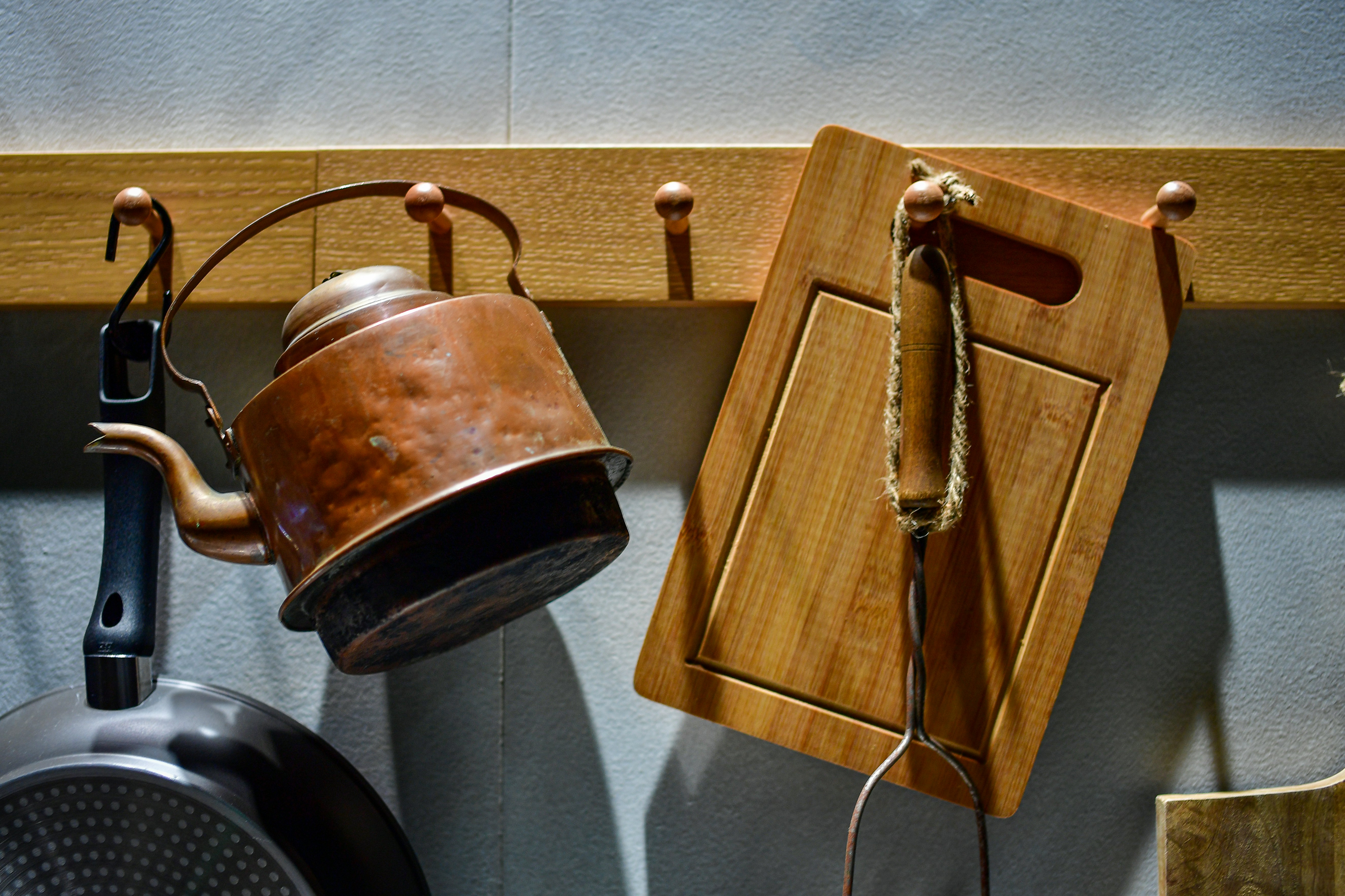 Un bollitore vintage e un tagliere appesi ai ganci.