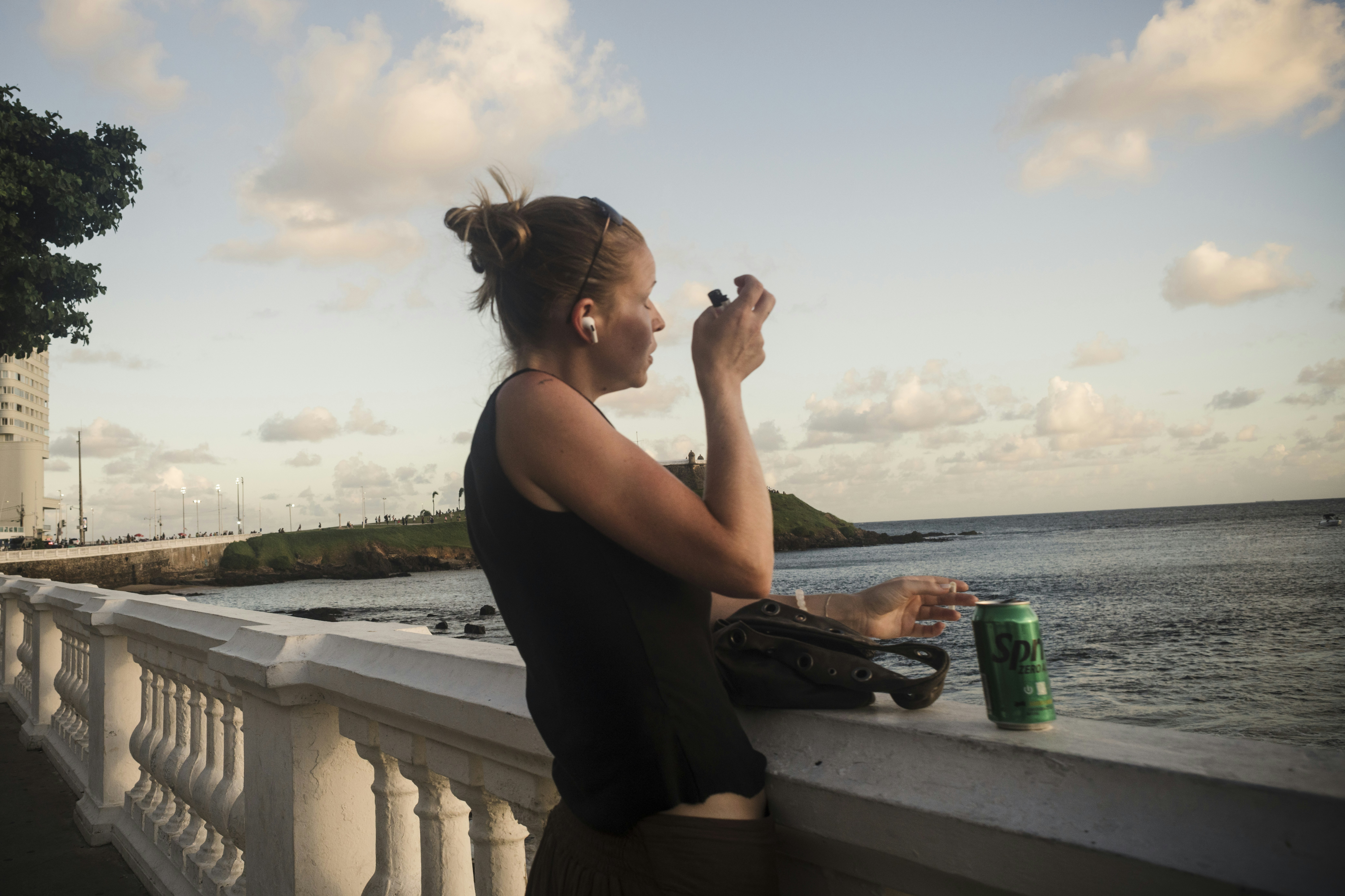 Woman holding cigarette and drink by the ocean
