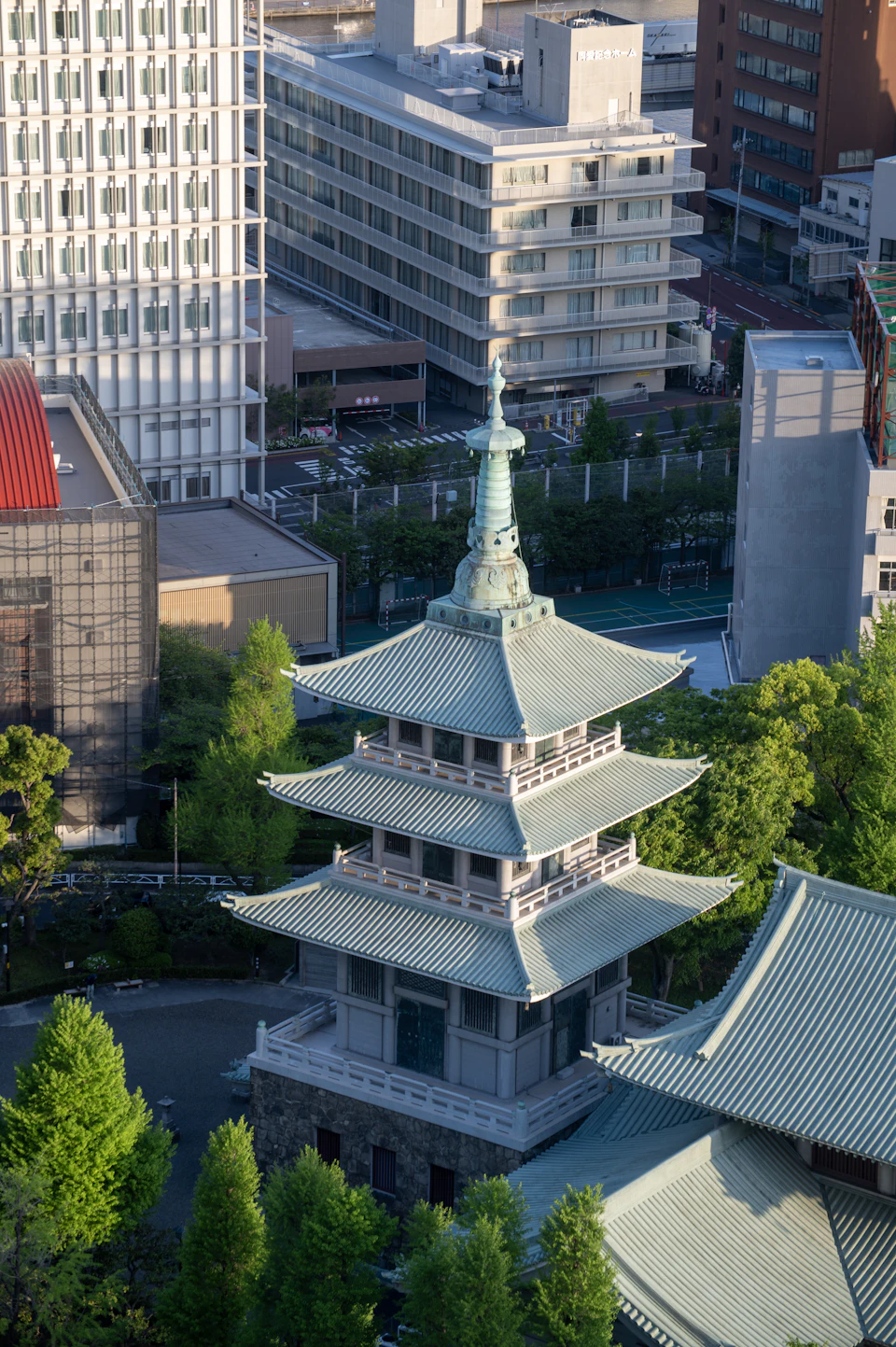 Central green pagoda with multiple tiers dominates cityscape at street corner surrounded by tall buildings