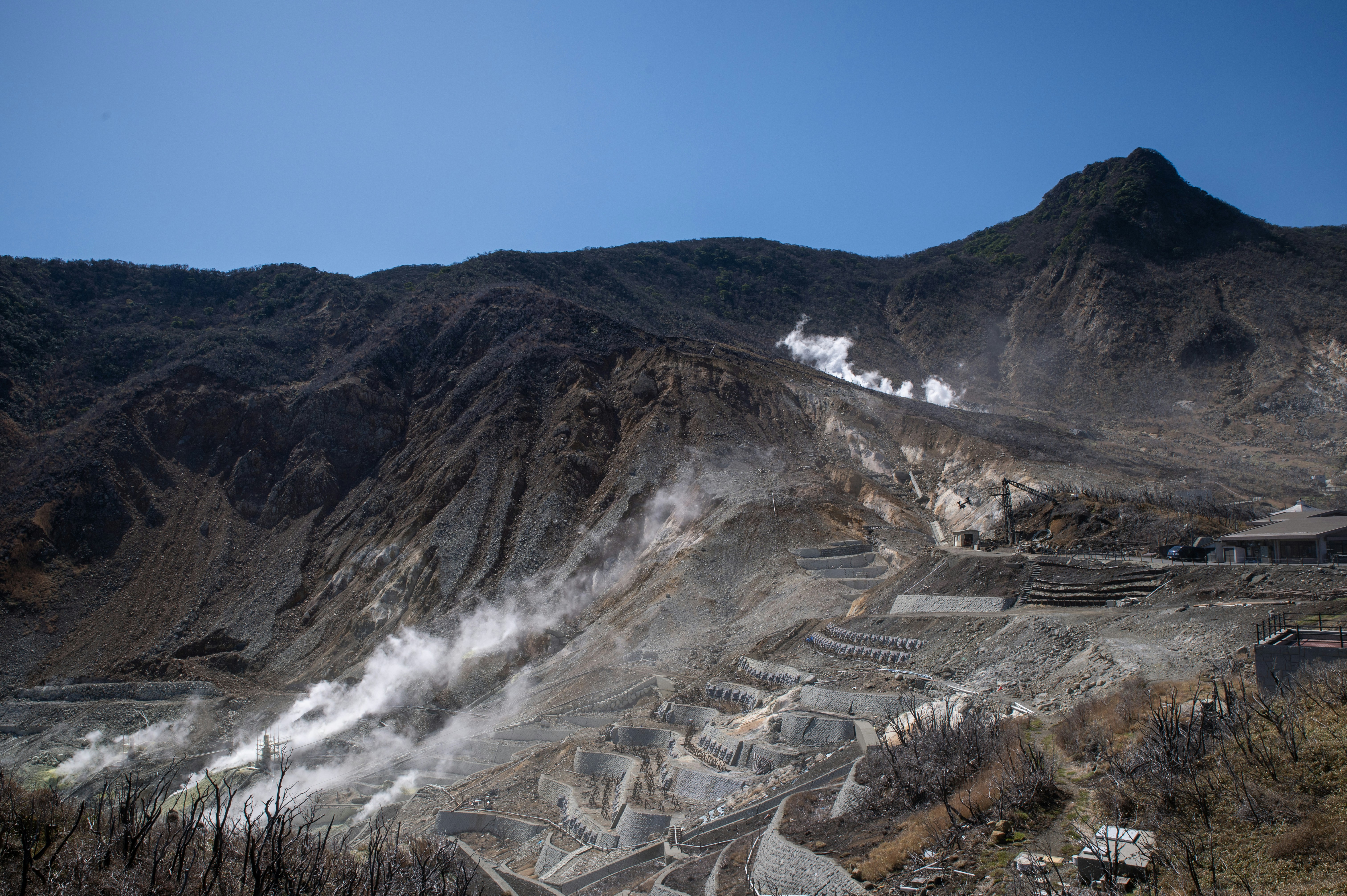 Volcanic landscape with steam vents and rocky mountains.