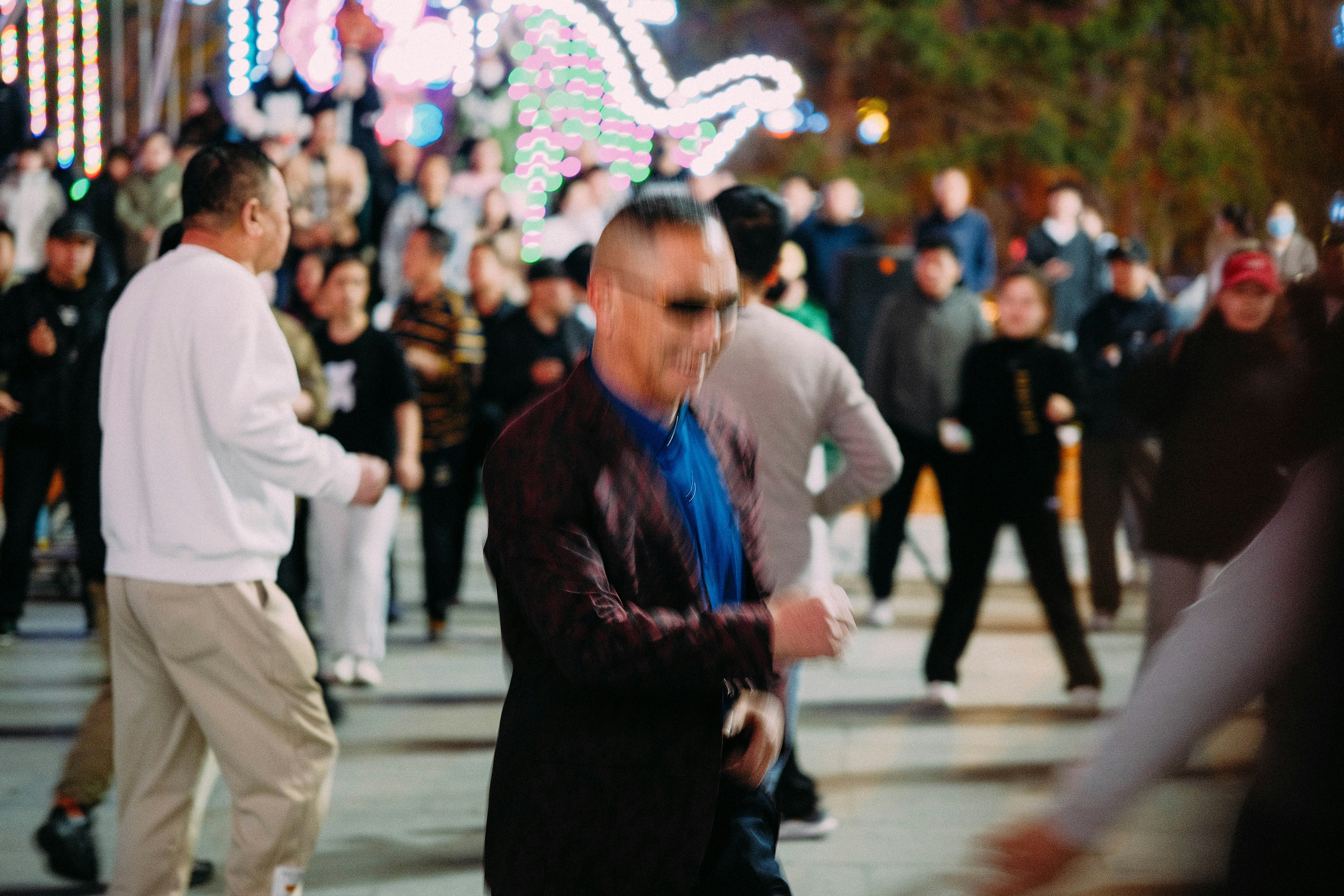 People dancing outdoors at night with lights